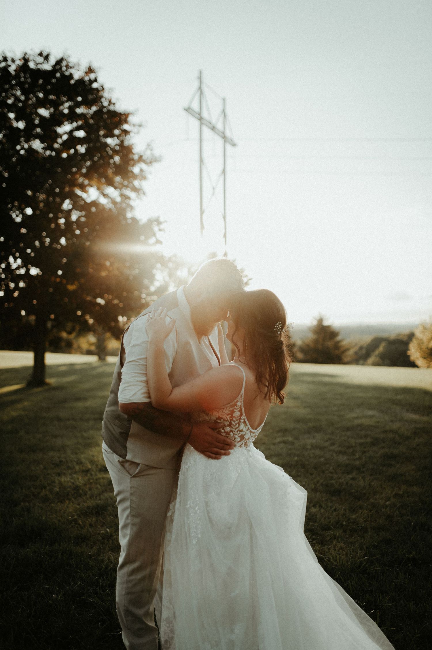 Intimate wedding kiss at golden hour with power lines and trees silhouetted in background. Pittsburgh Wedding Photographer