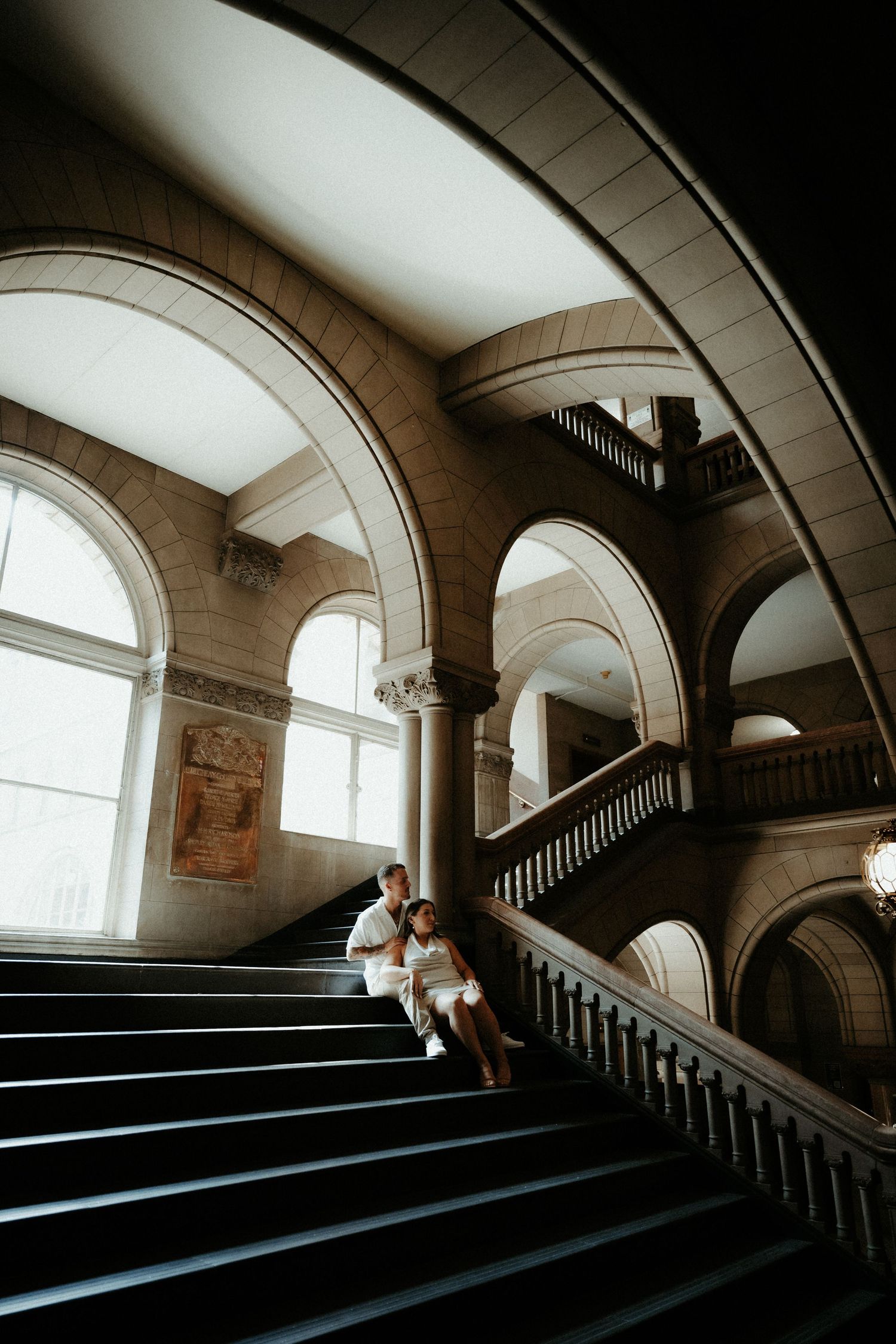 A sequence of architectural photos showing a dramatic curved staircase with arched windows in an elegant historic building.