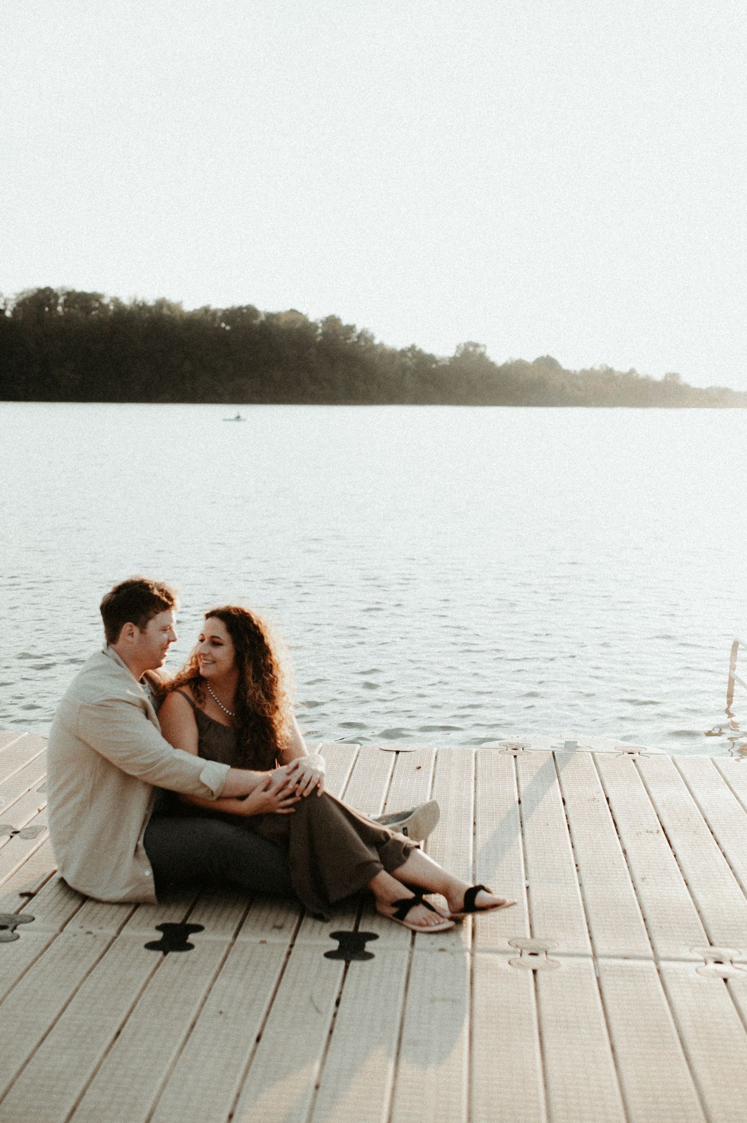 Couple sitting together on wooden dock by serene lake at sunset. Pittsburgh Wedding Photographer