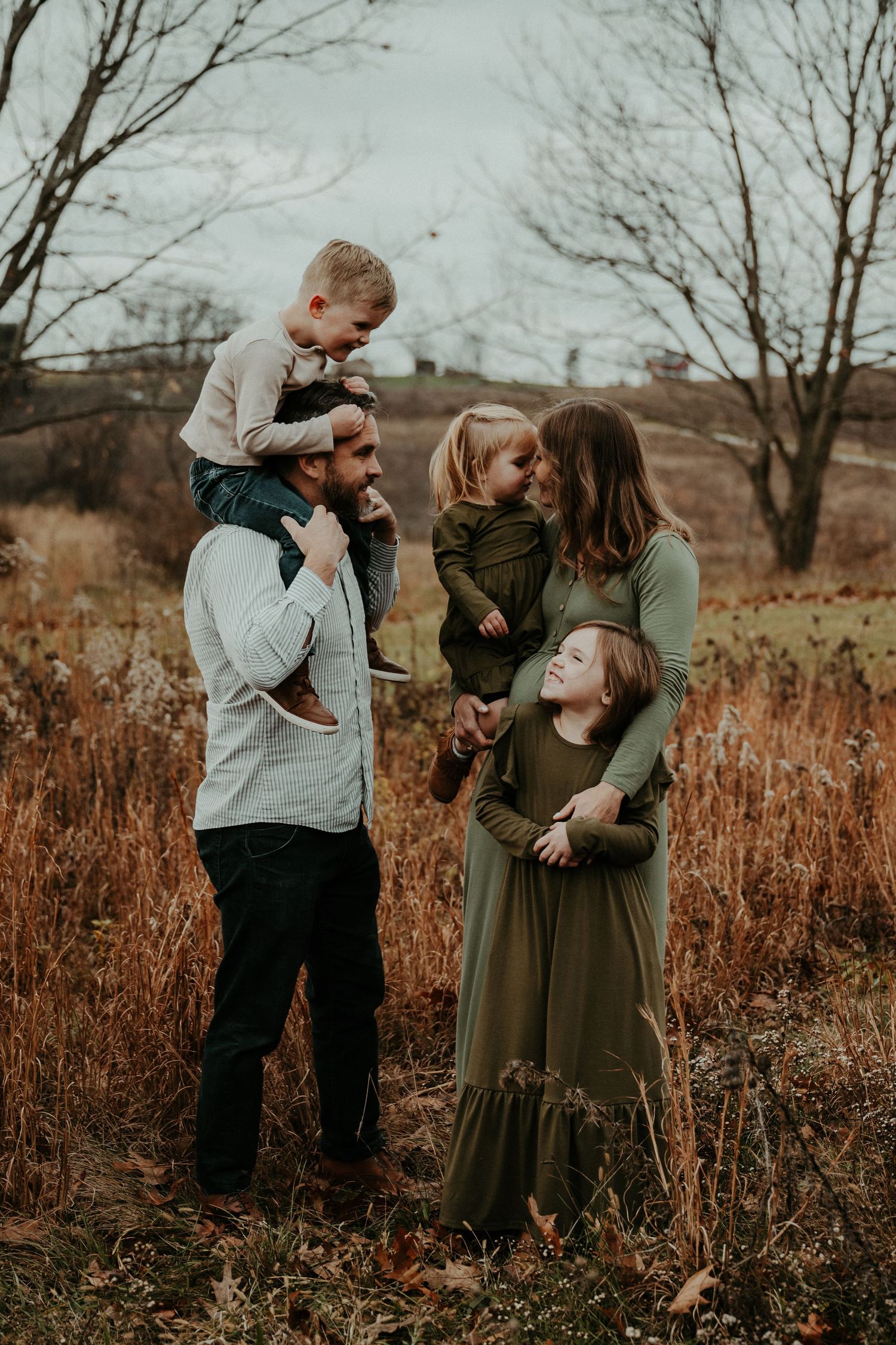 A family shares joyful moments together in an autumn field at sunset.