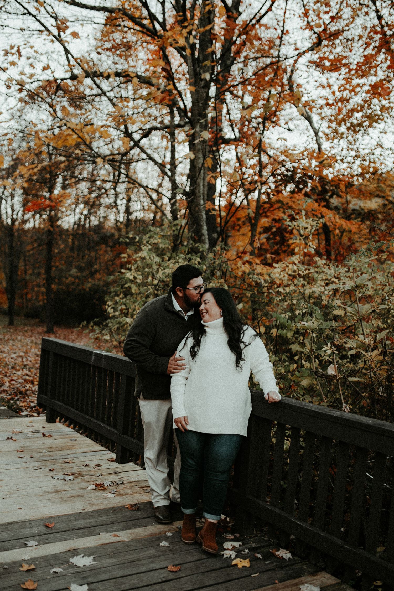 Couple shares intimate moment on wooden bridge surrounded by fall foliage. Pittsburgh Wedding Photographer