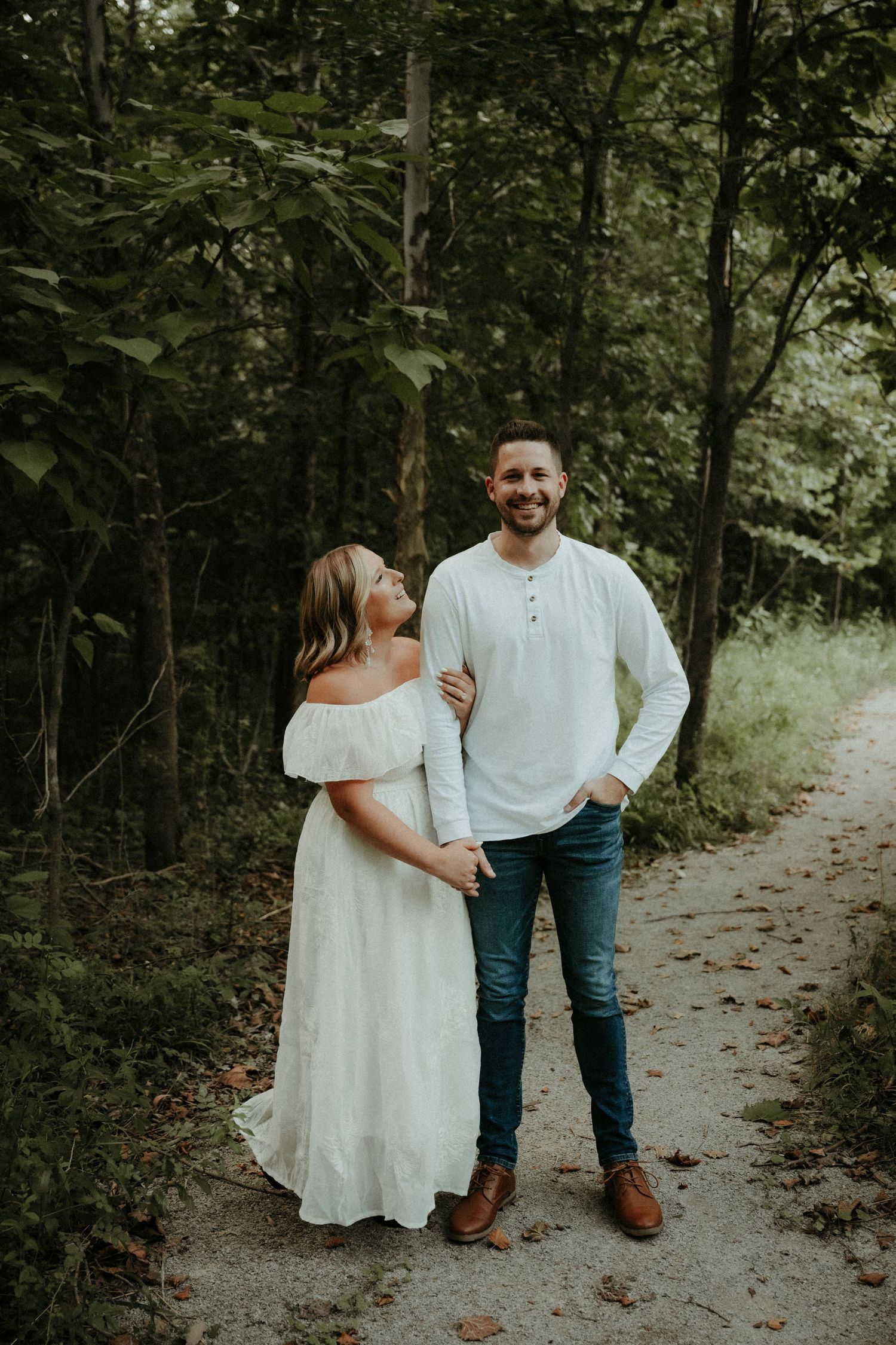 A couple stands together on a forest path during a romantic outdoor photo session in soft natural lighting. Pittsburgh Wedding Photographer