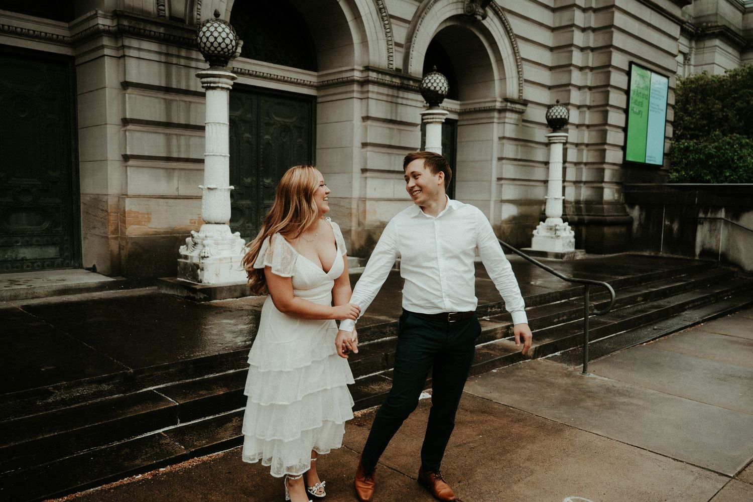 A couple shares a moment outside a historic stone building with arched columns and architectural details. Pittsburgh Wedding Photographer