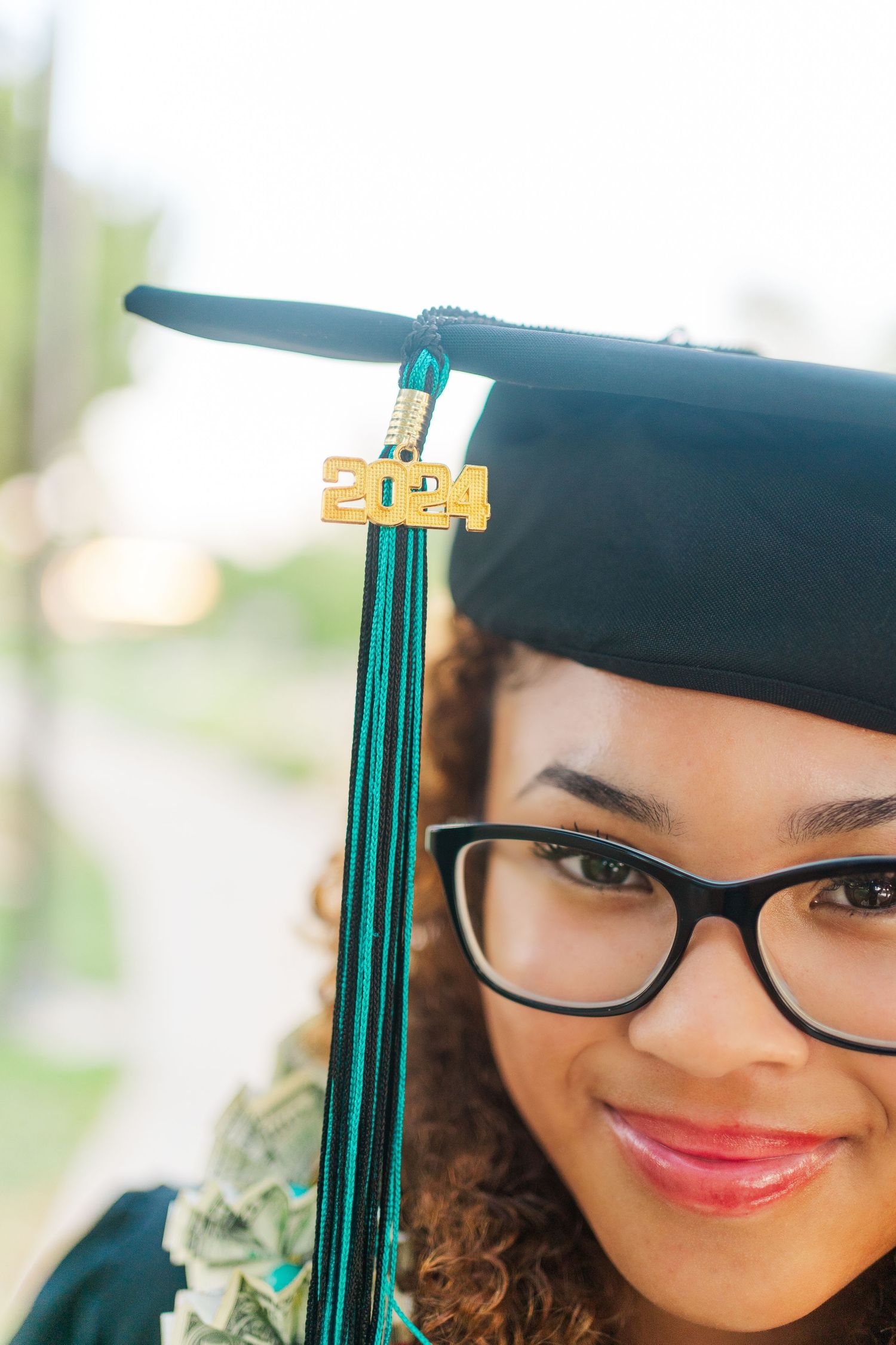Close-up graduation photo showing a cap with 2014 tassel and glasses against blurred background.