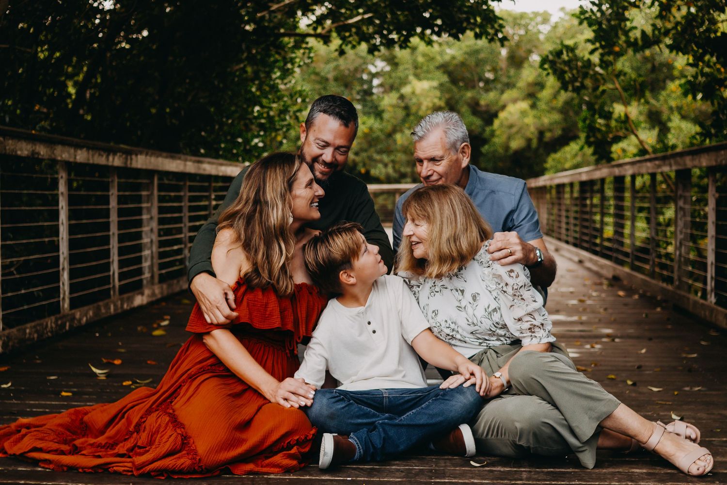 A group relaxes and shares intimate moments together on a wooden bridge surrounded by lush greenery.
