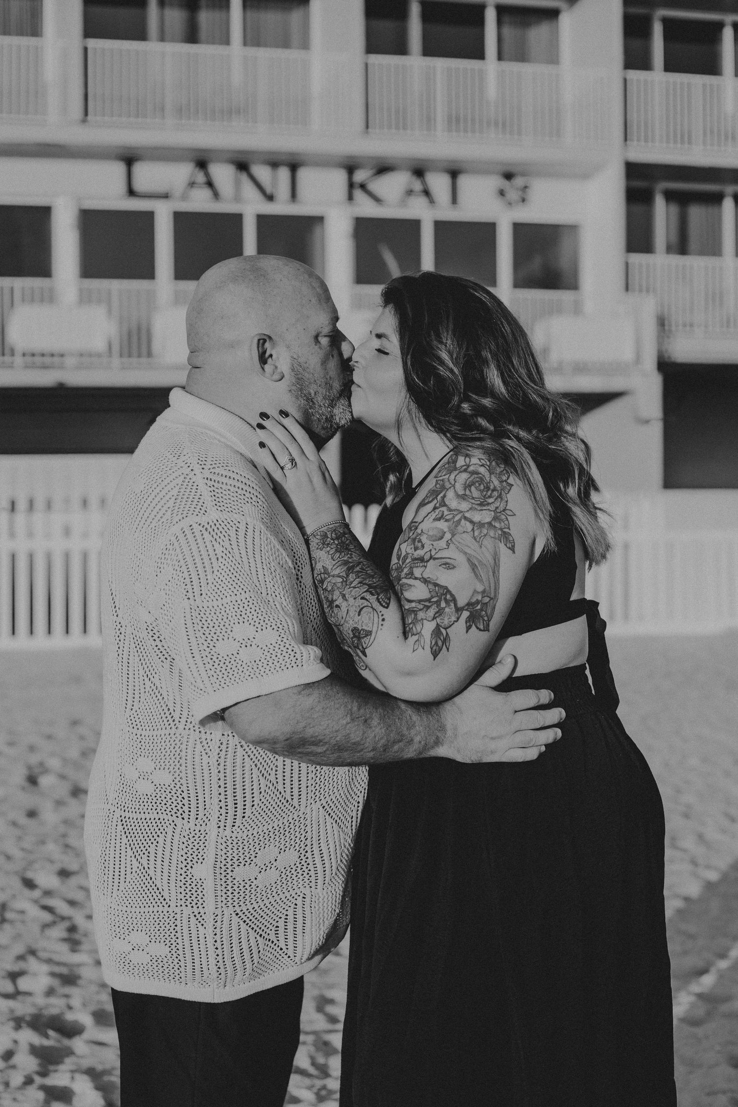 A series of three black and white photos showing a couple embracing and kissing on a beach.