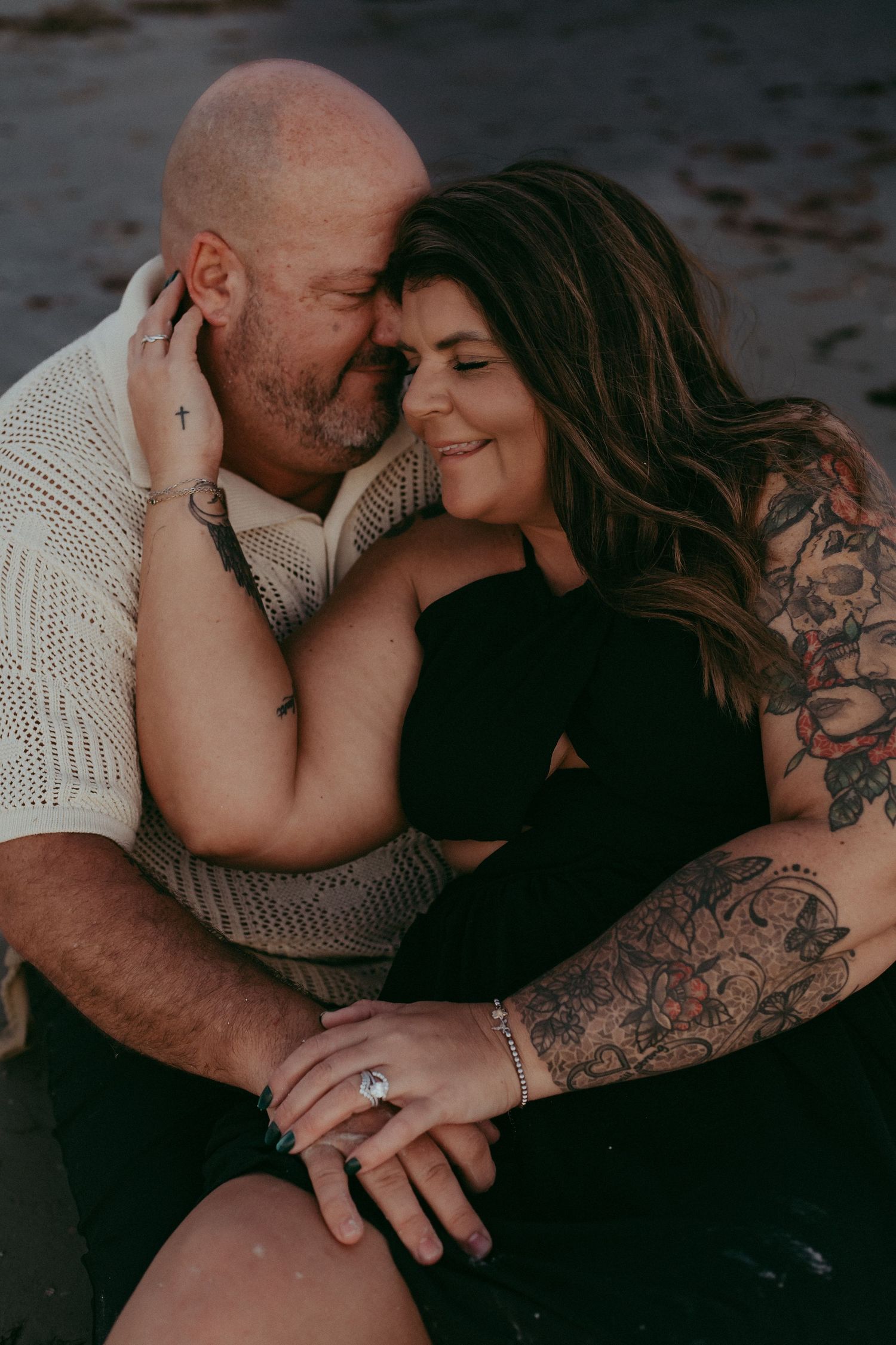A romantic couple with tattoos share intimate moments in a series of dark, moody photographs.