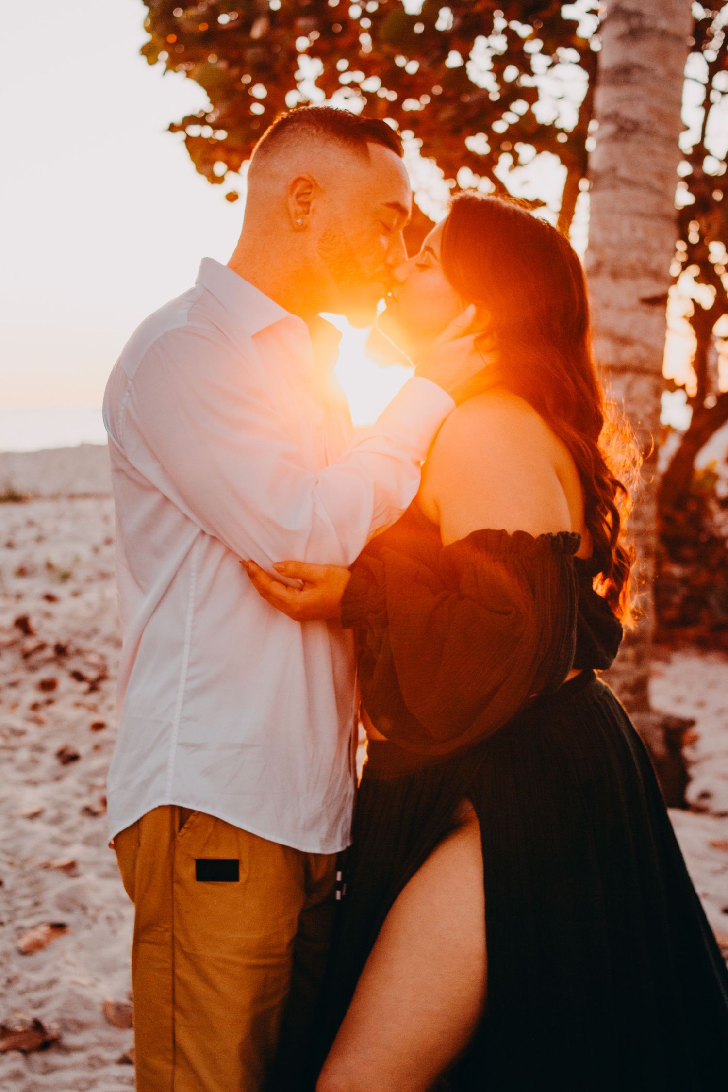 Romantic couple embraces in warm sunset light among birch trees creating a dreamy silhouette effect.