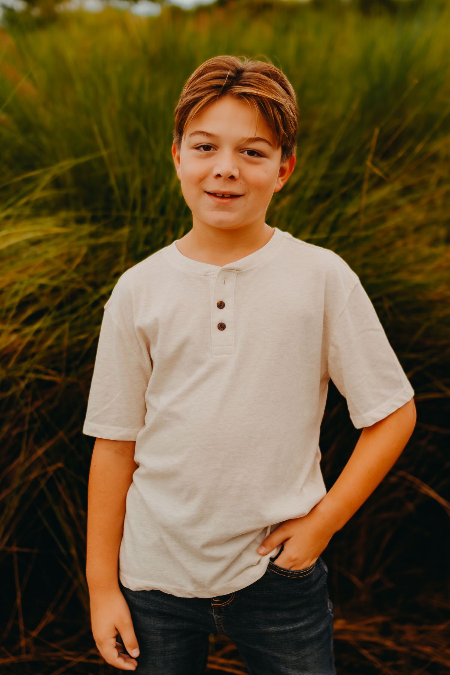 A series of outdoor portrait shots showing a young child in a white henley shirt against tall grass at sunset.