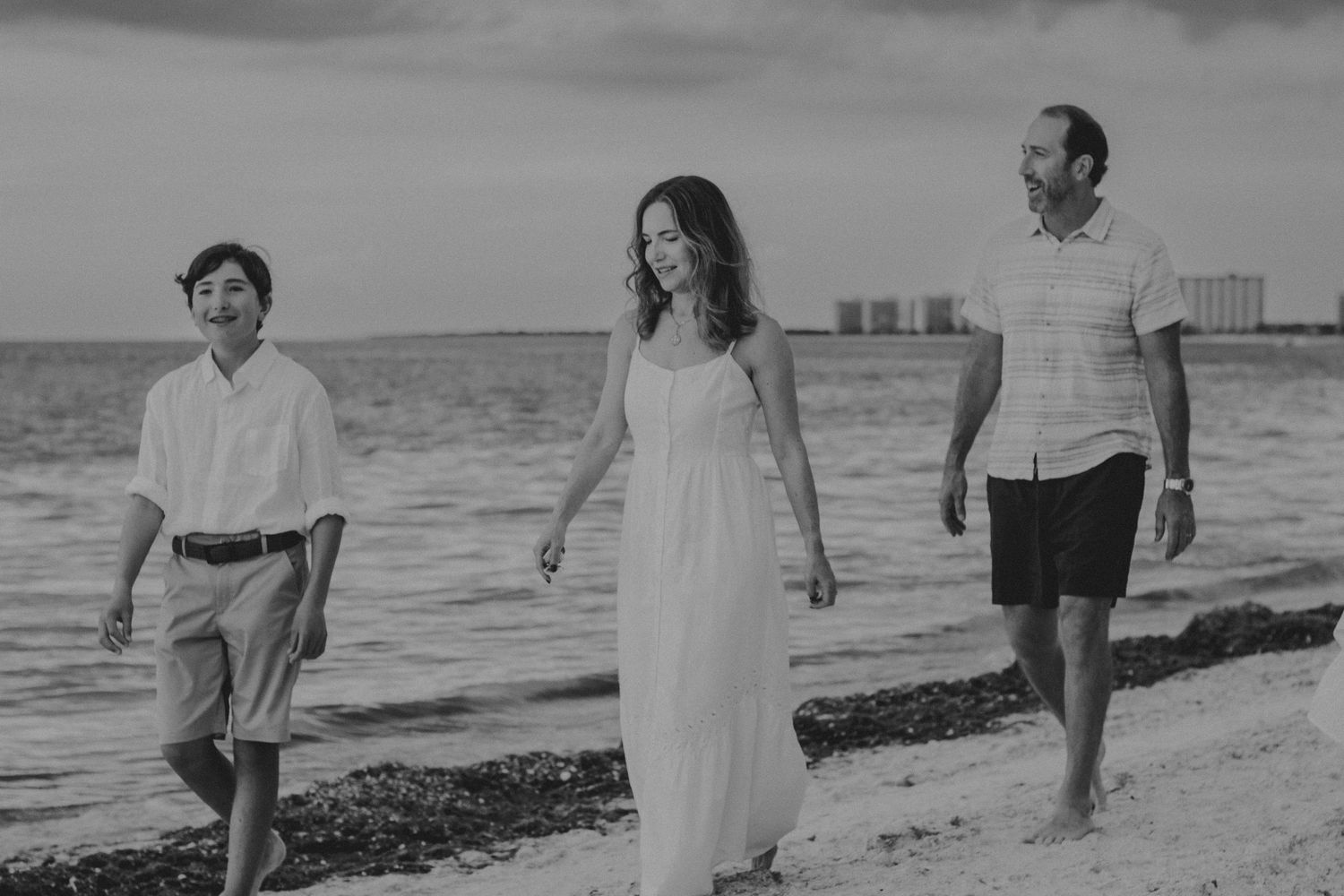 A black and white photo sequence shows people walking along a beach shoreline at sunset.