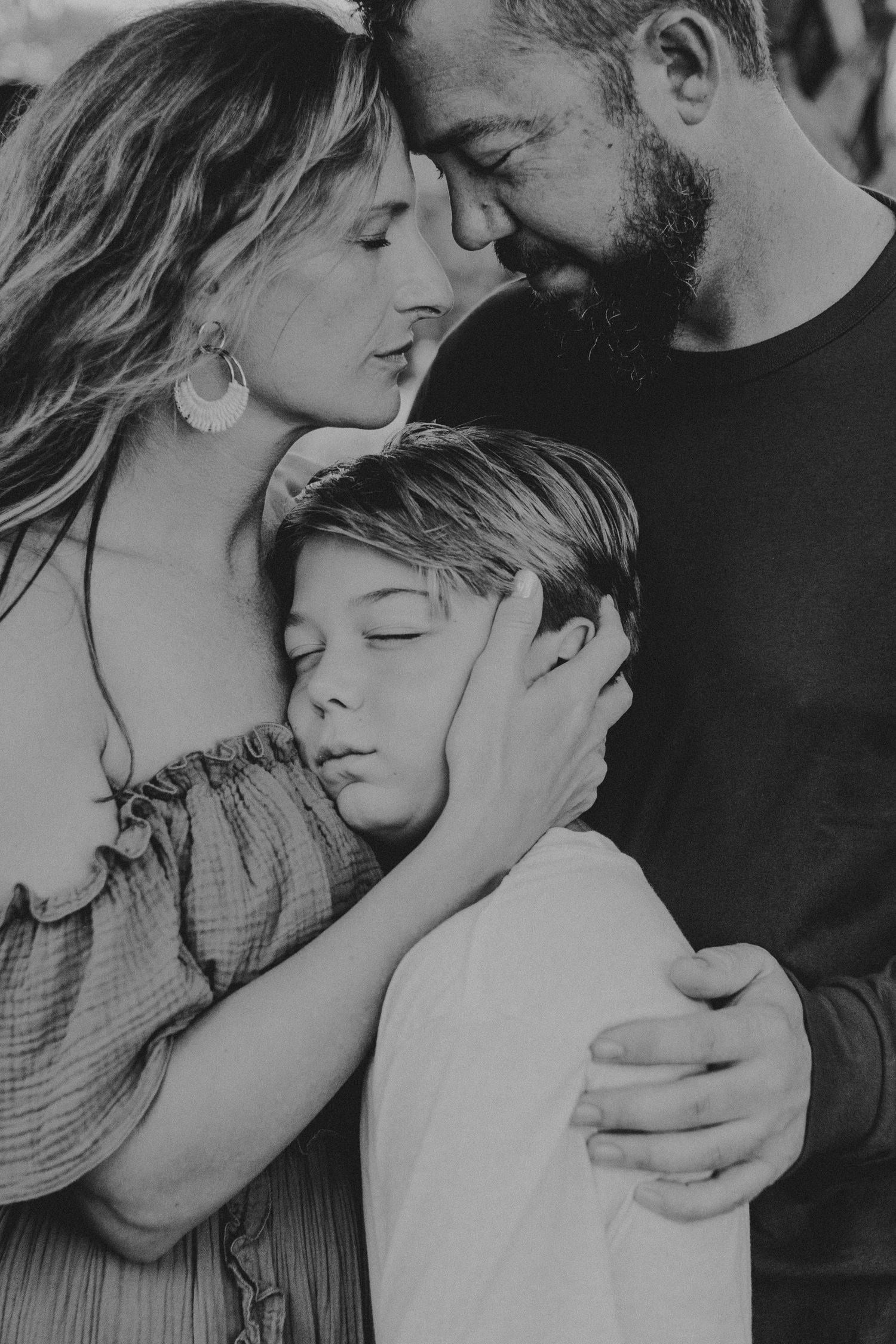 A tender black and white collage of intimate family moments showing parents embracing their child with love and affection.
