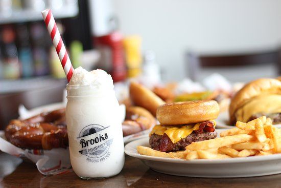 A collage of breakfast foods and drinks including pancakes, french fries, milkshakes with striped straws and a glass bottle.