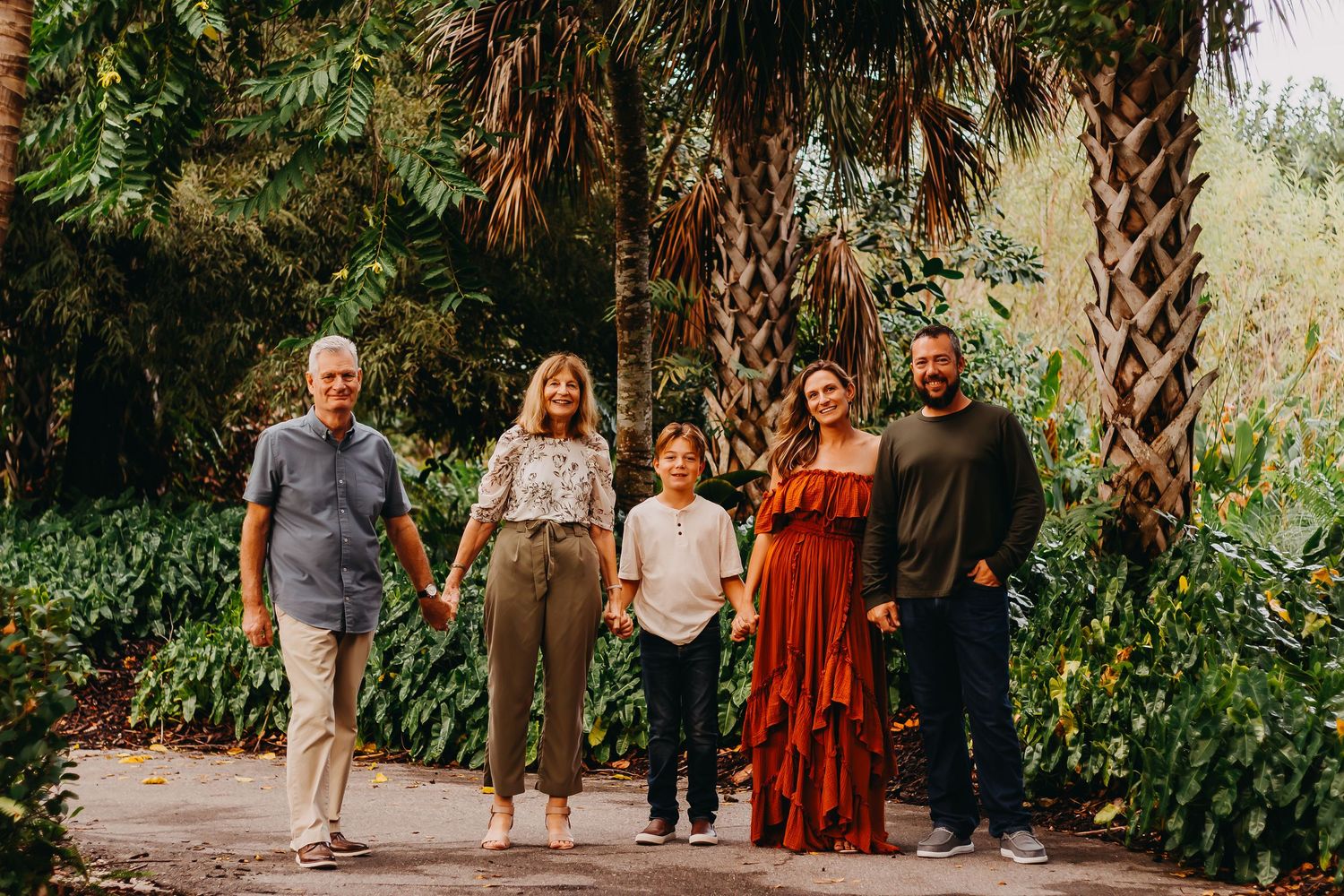 A group of people walking together on a tree-lined path during a sunny day.