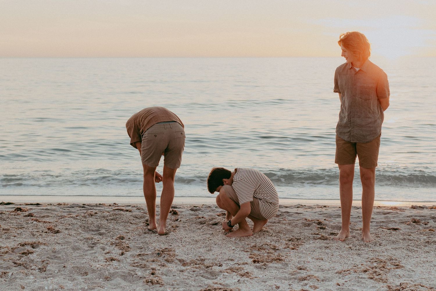 People walking and playing on a sandy beach at sunset while enjoying the peaceful ocean view.