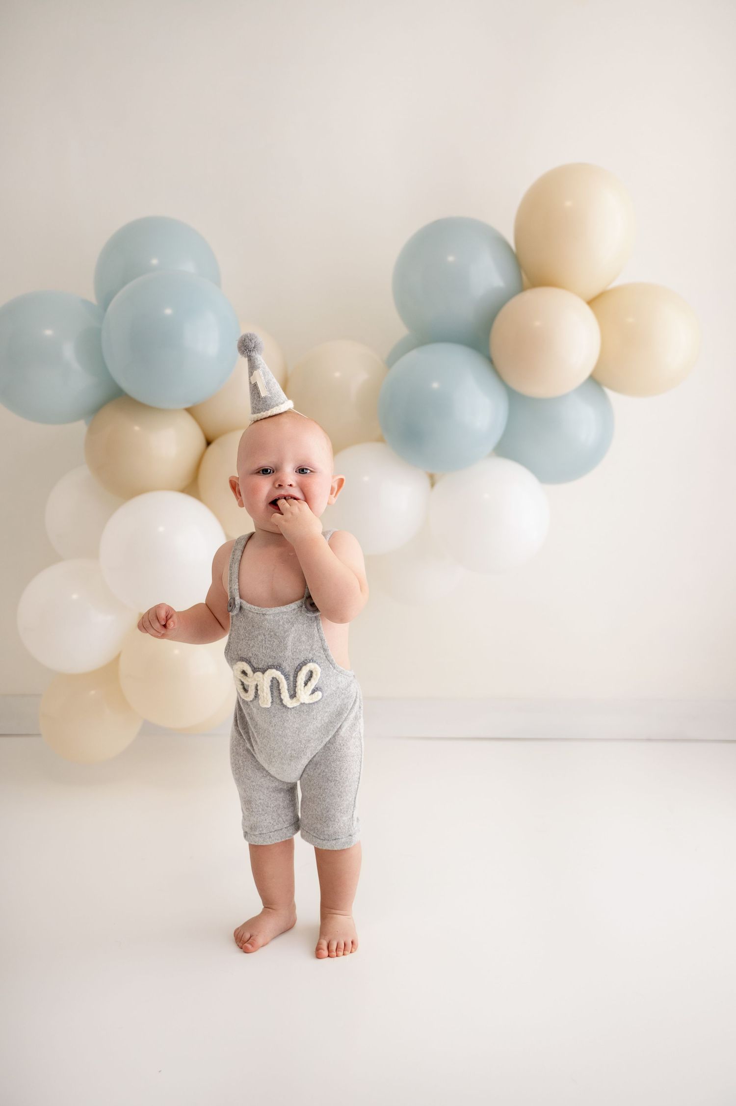 First birthday celebration setup with blue, white and cream balloon arch decorations and festive party attire.