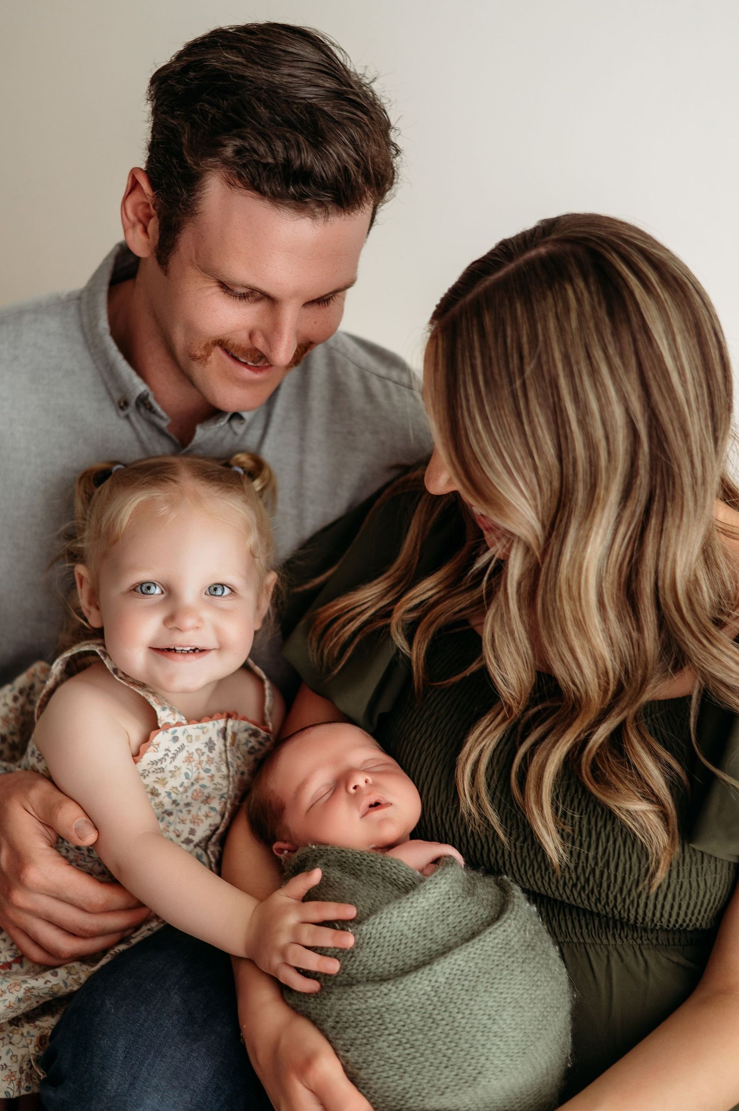 Candid family moment showing tender interactions between parents and toddler on a cozy couch.
