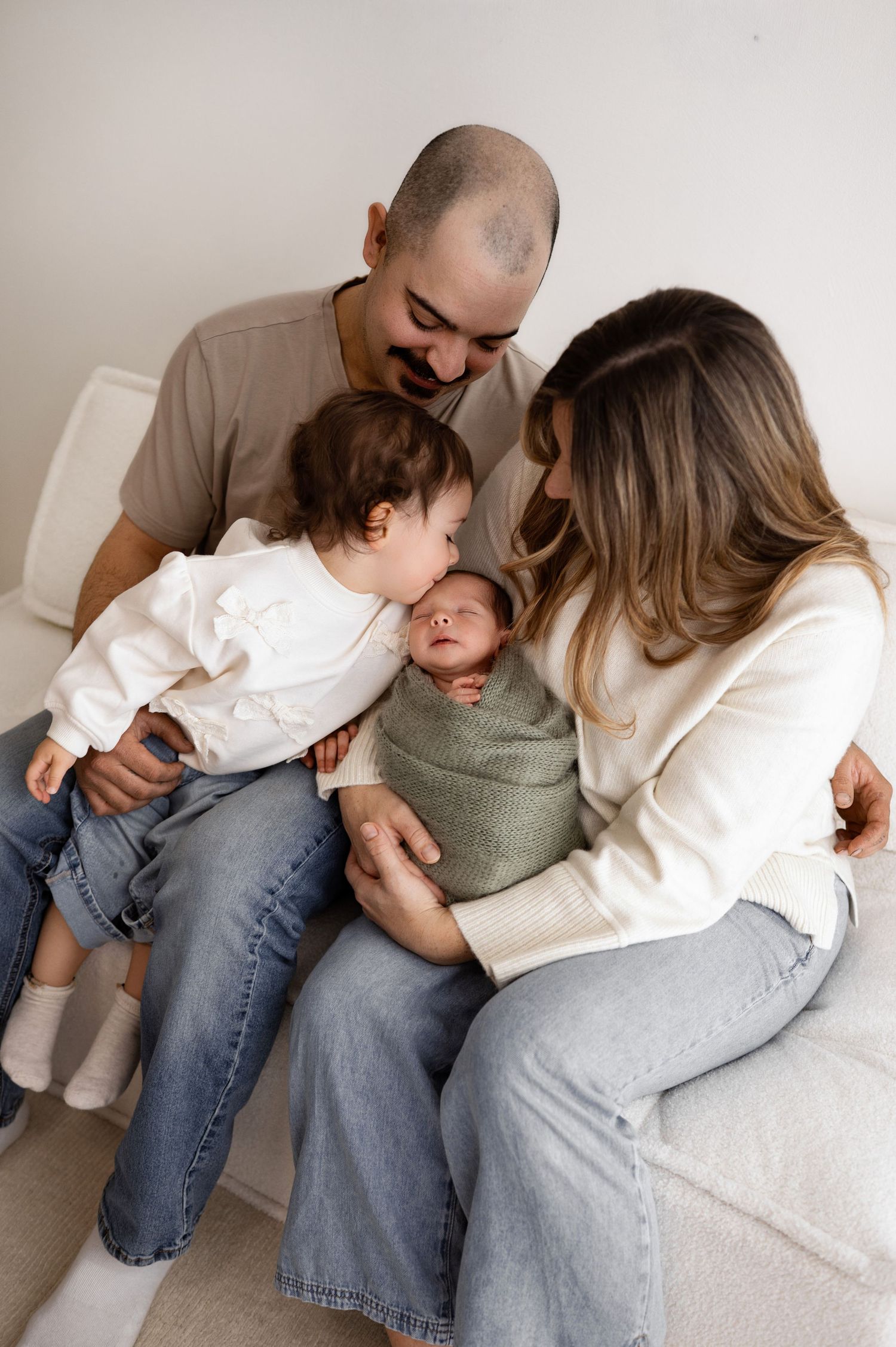 Candid family photography series showing playful interactions on white sofa.