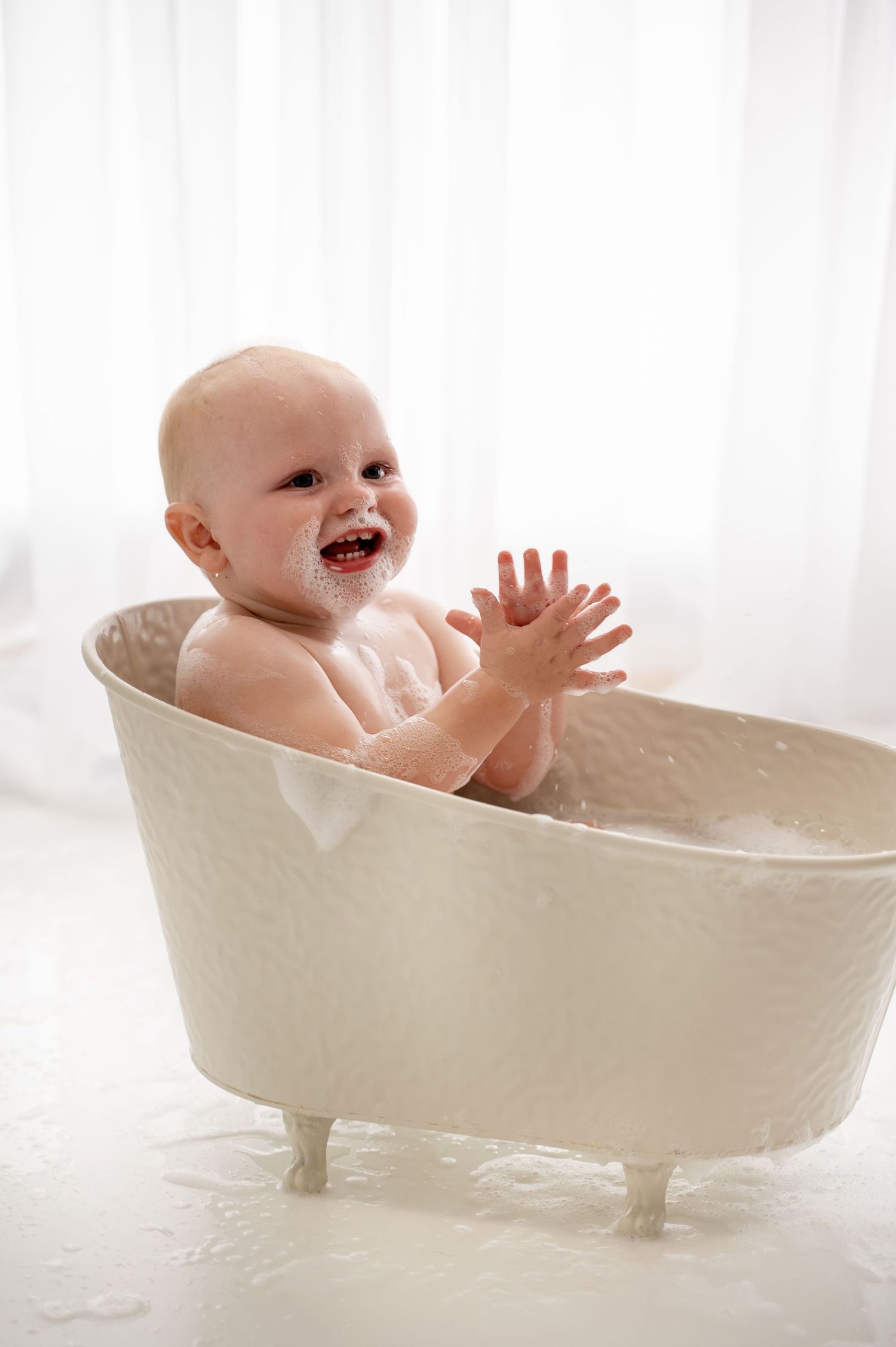 Series of photos showing a happy baby playing in a vintage-style white clawfoot bathtub during bathtime.