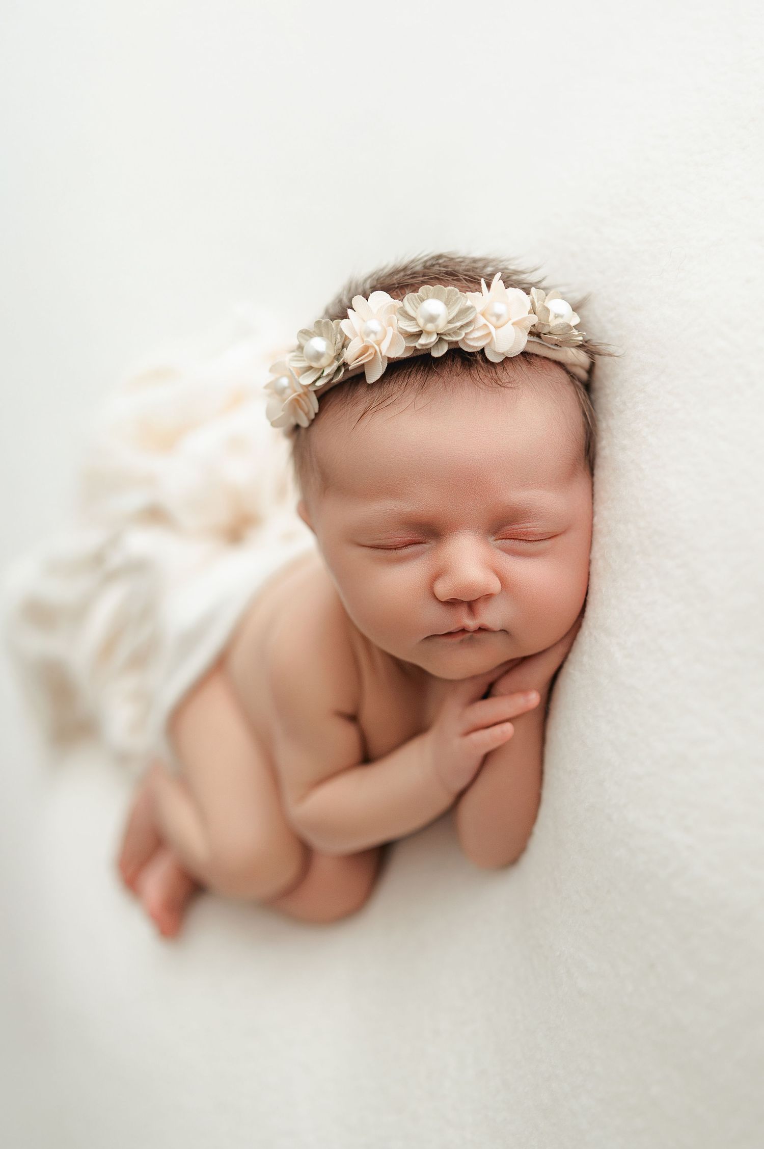 A peaceful baby sleeps with a delicate white floral crown against a soft white backdrop in three artistic poses.