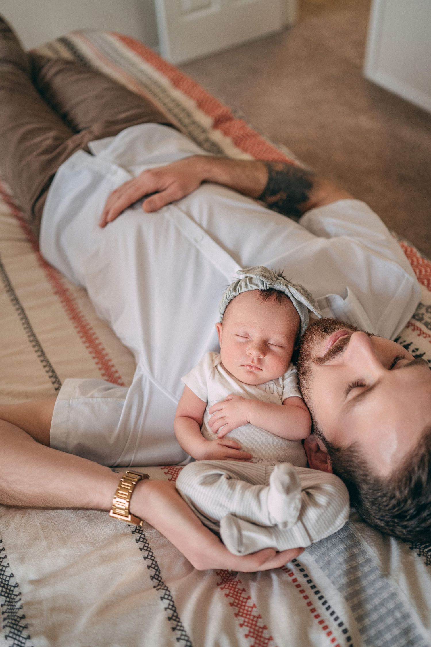 Baby sleeping on soft blanket while resting adorably against adult figure in peaceful home setting.