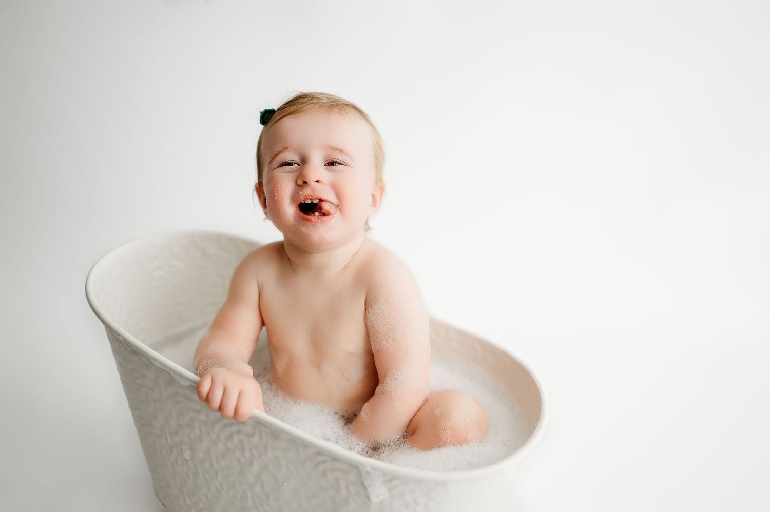 Happy baby sits in a white ceramic bathtub during bath time, showing joyful expressions in a series of photos.