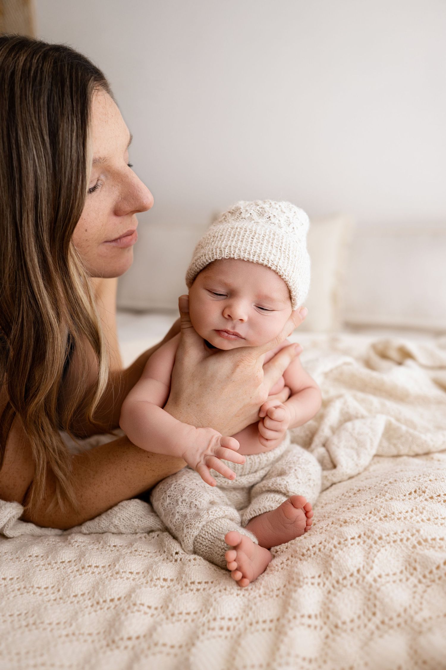 A series of intimate newborn photography shots on cream bedding showing tender moments with soft natural lighting.