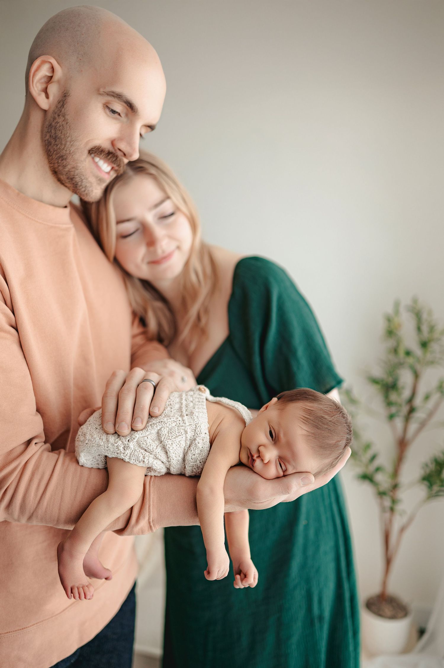 A series of tender moments showing a couple holding and cradling a newborn baby in soft peach and emerald tones.