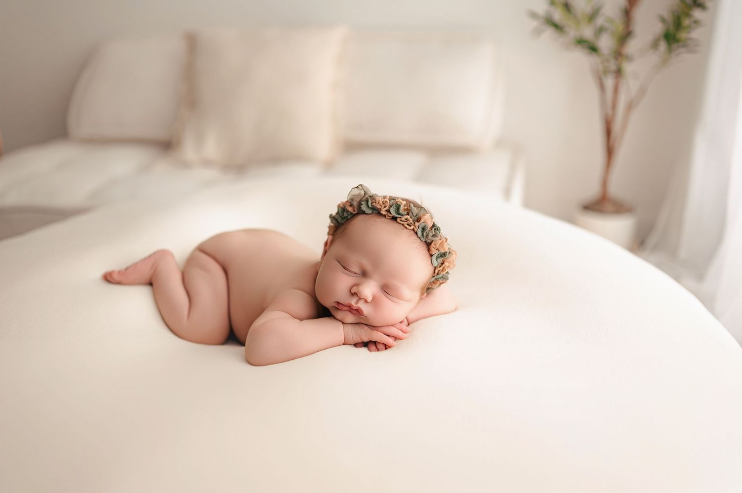 A sleeping newborn baby lies peacefully on soft white bedding in a series of dreamy, ethereal photos during a studio session with Mellaa Pho