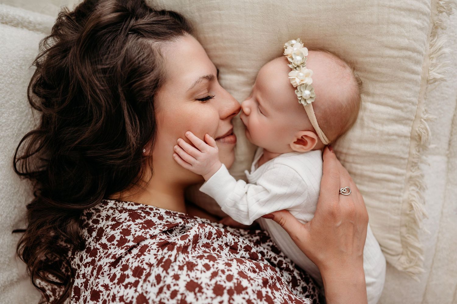 A sweet intimate moment as mother and baby share affection on cozy bedding.
