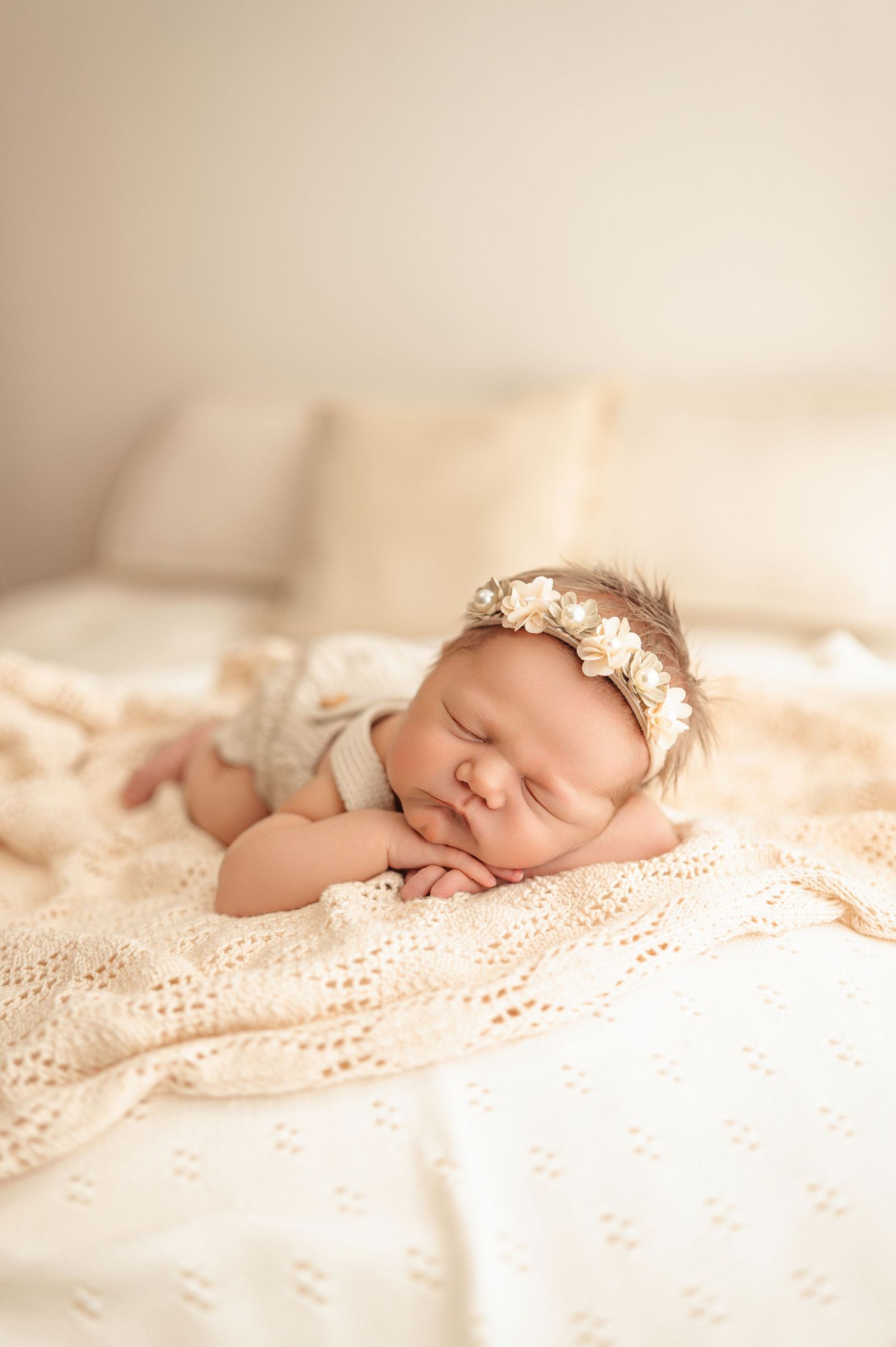 Peaceful newborn baby sleeping on soft lace blankets in dreamy natural light setting.
