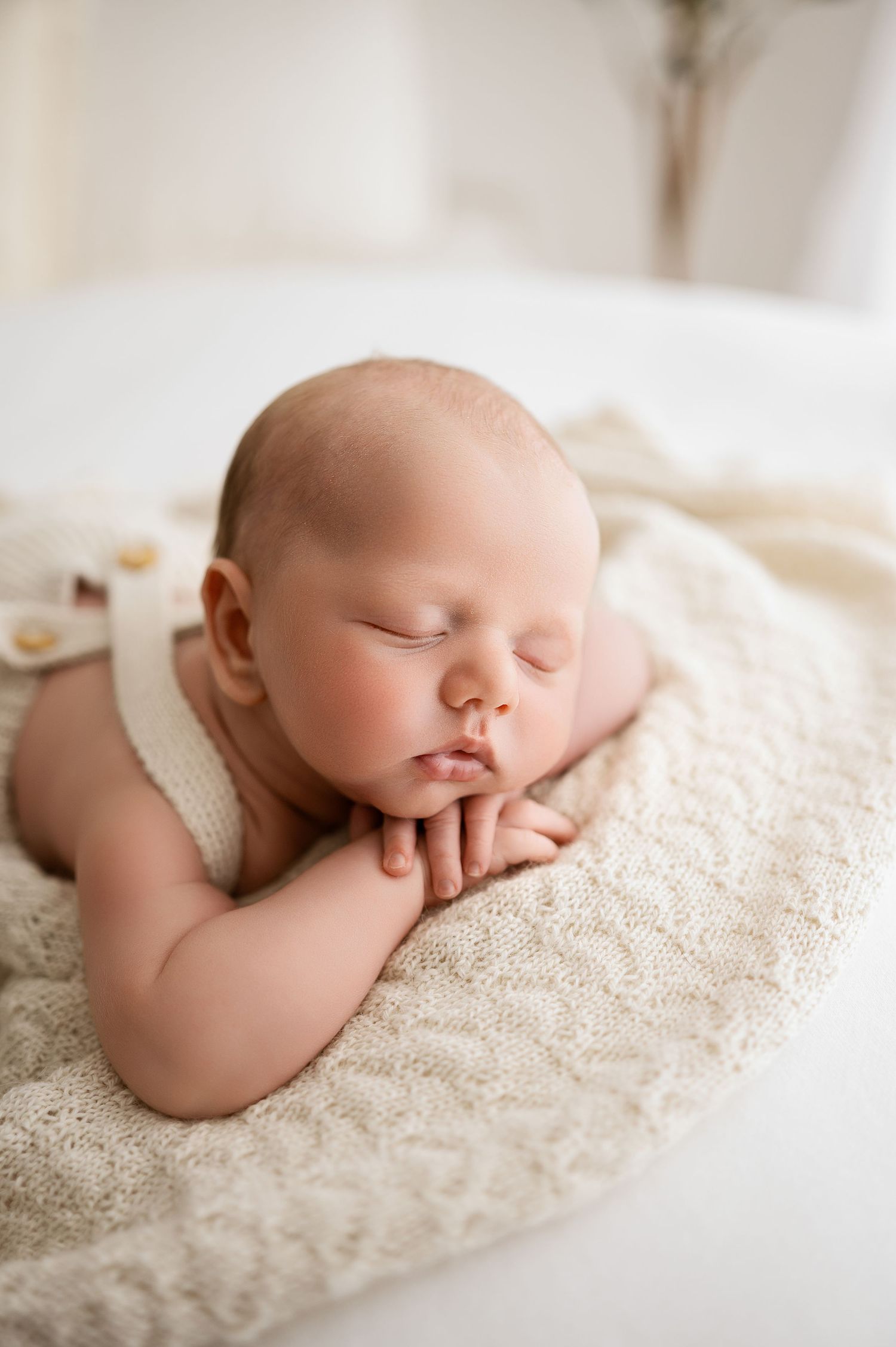 A sleeping newborn baby rests peacefully on soft cream-colored lace fabric in a series of gentle poses.
