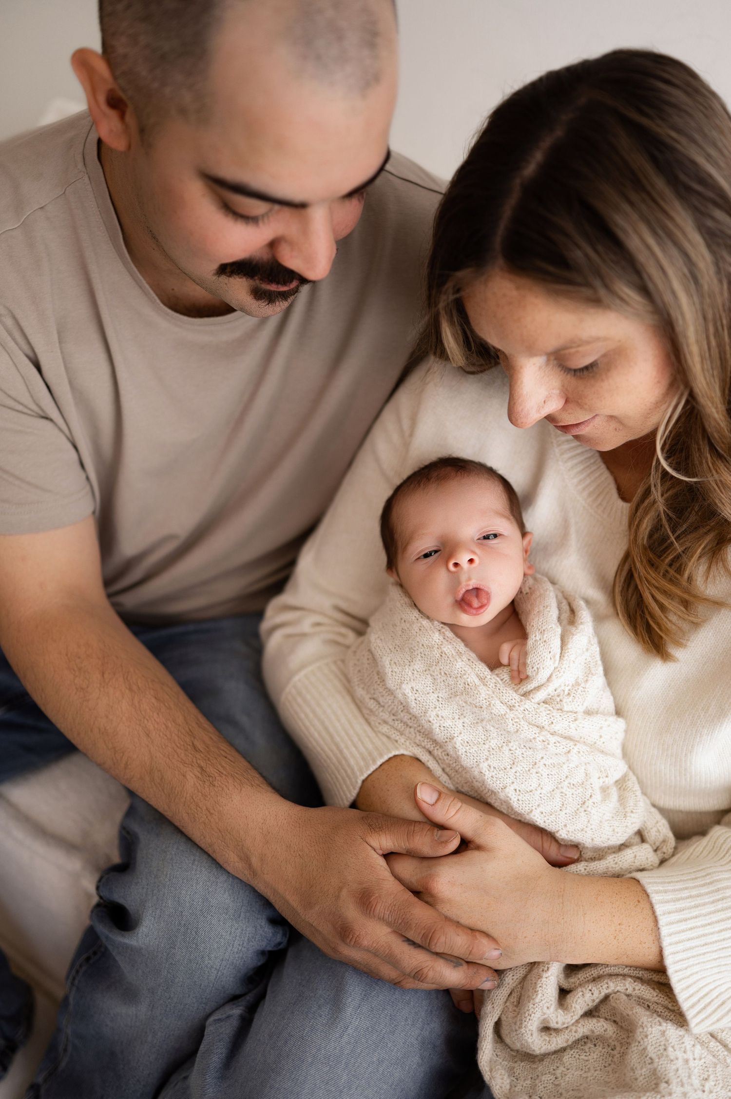 Intimate family moments captured in series showing parents cuddling with young child on white background.