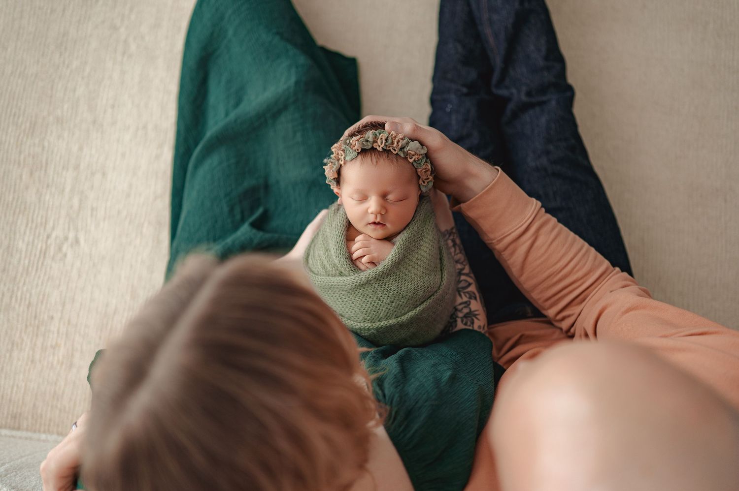 A sleeping baby in a cozy onesie lies with blankets in a tranquil swaddled pose against a soft neutral background.
