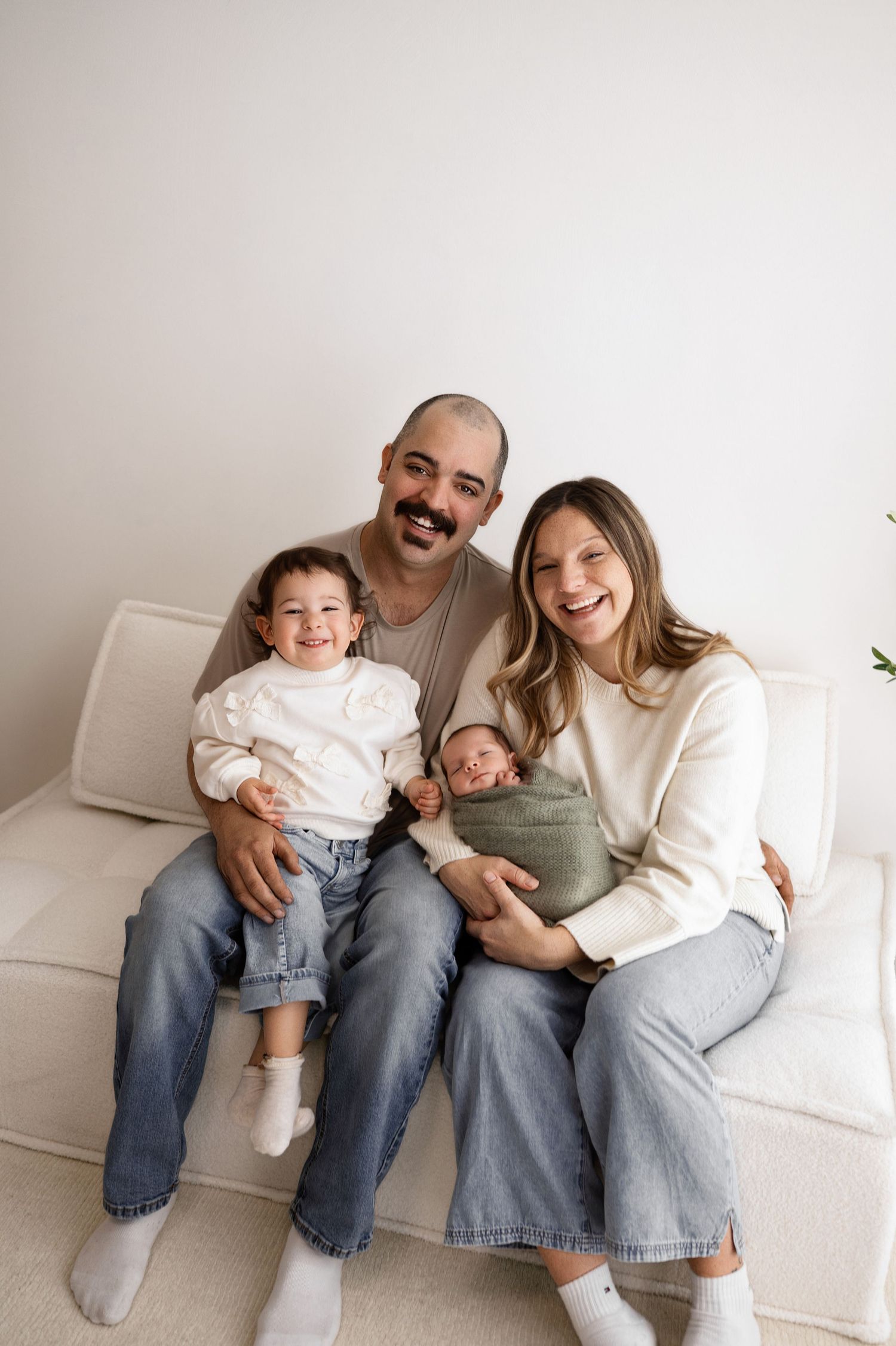 Casual family portrait series showing relaxed moments together on white couch.