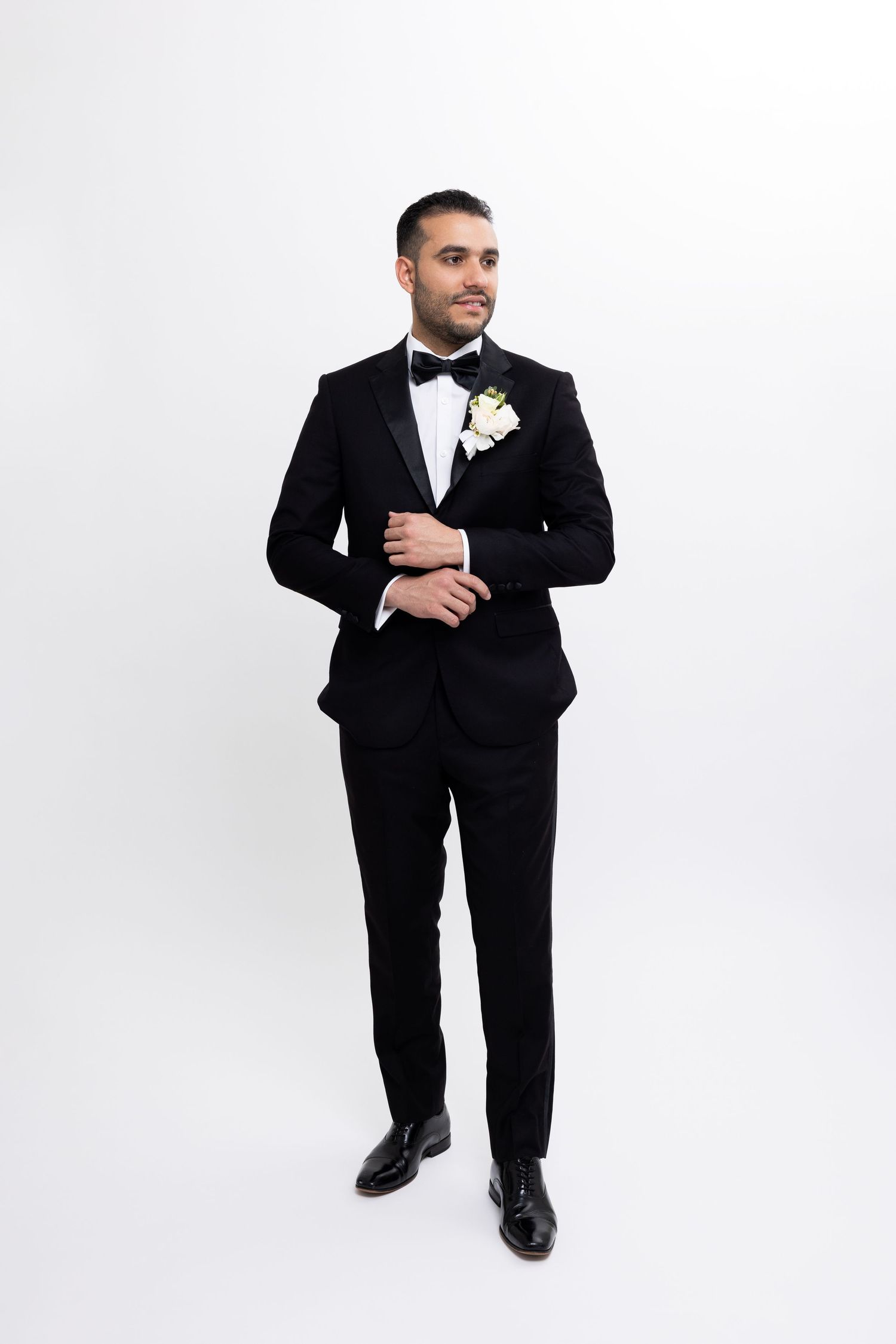 Classic black tuxedo with bow tie and white boutonniere on white background.