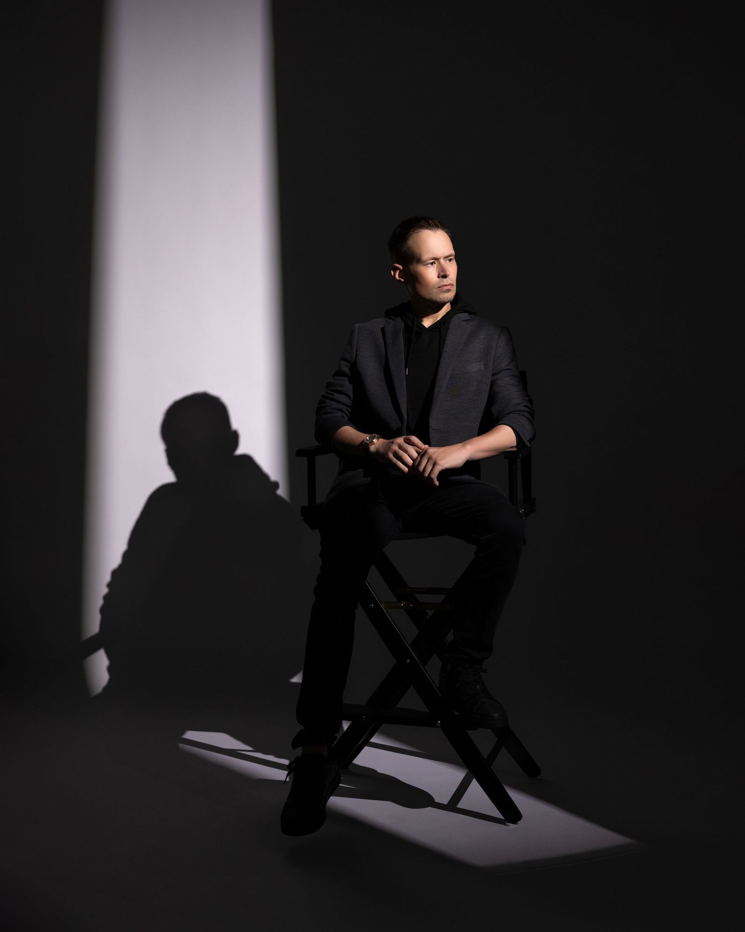 A dramatic black and white portrait series showing a figure in dark clothing against a stark white backdrop with deep shadows.