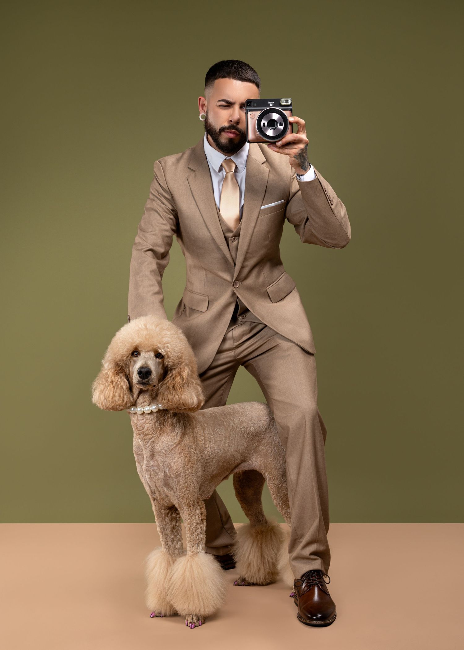 Professional studio portraits featuring a standard poodle and someone in a tan suit posing against an olive background.
