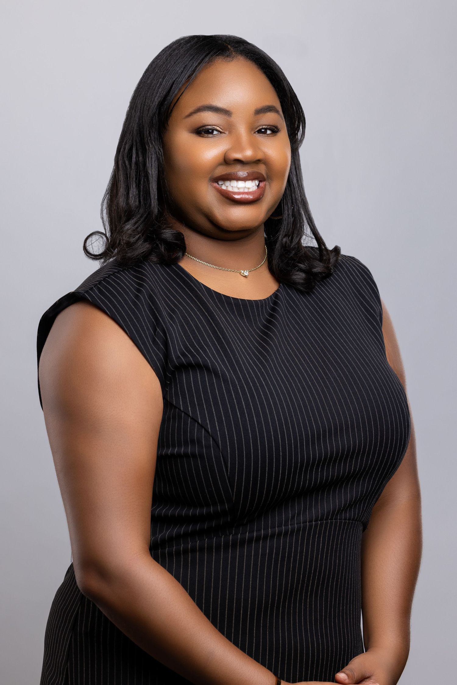 Professional headshot series of a person wearing a sleeveless black pinstripe dress against a gray background.