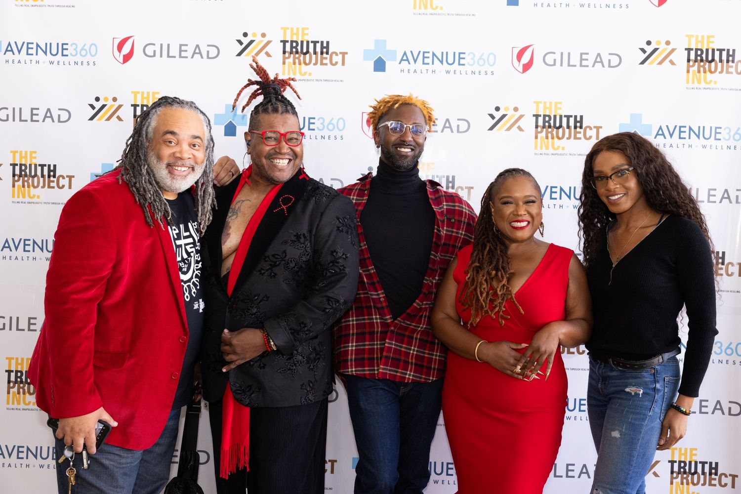 A group poses together at a media event with Gilead logos visible on the backdrop wall.