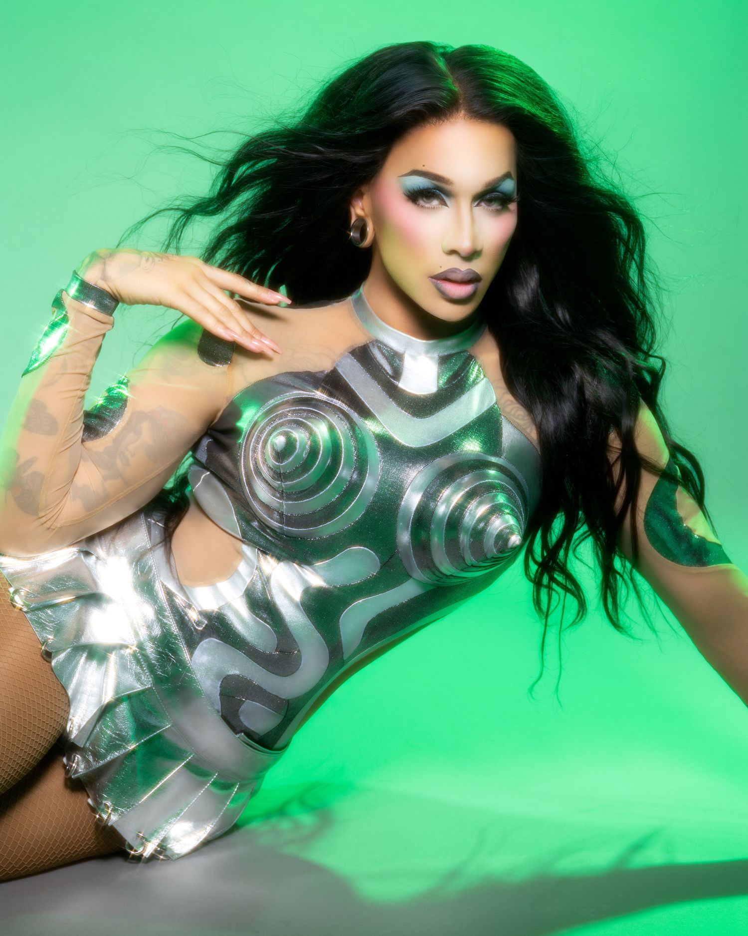 Fashion model in metallic bodysuit poses dramatically against bright green background in artistic photo sequence.