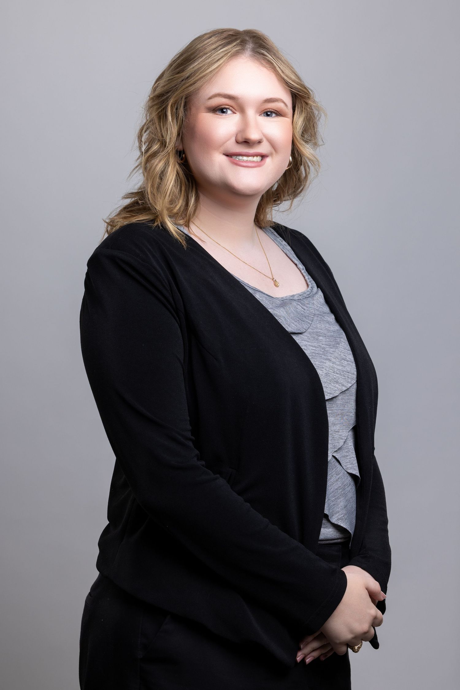 Professional studio portrait series showing a person in a black blazer and gray top against a neutral gray backdrop.