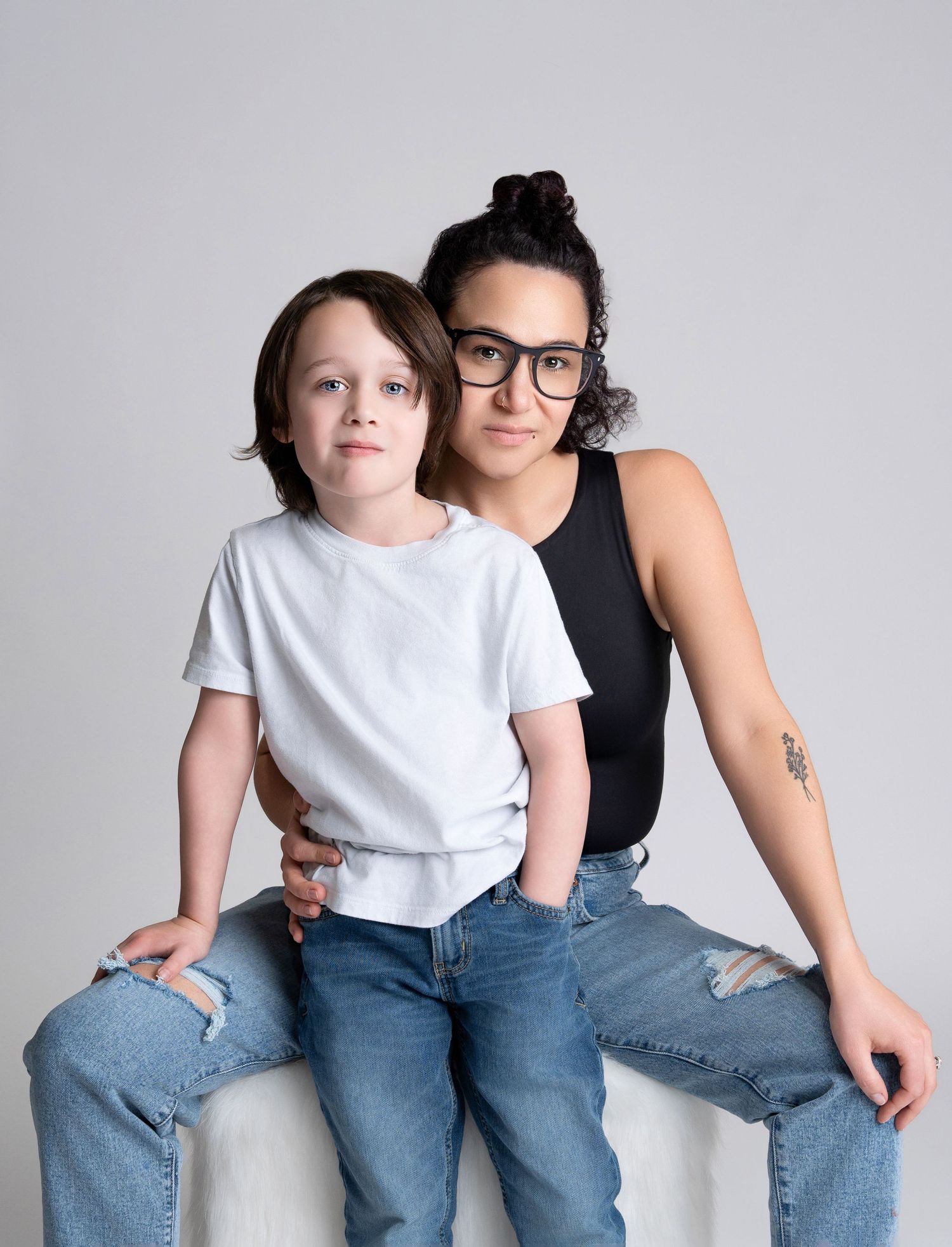 a mother sits with her son in a white studio during motherhood photos