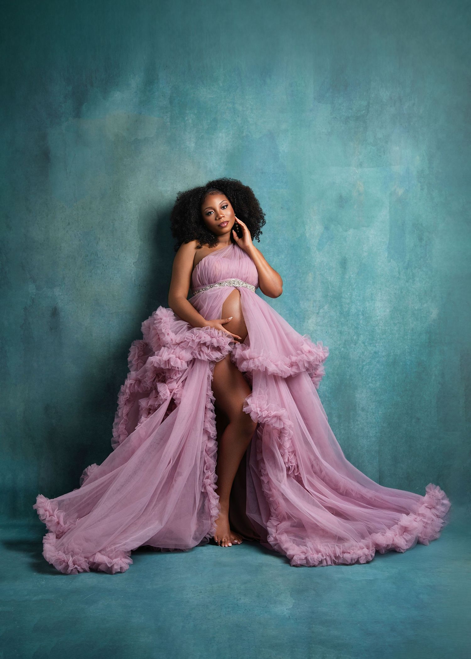 A series of stunning maternity portraits featuring a flowing pink tulle gown against a teal textured backdrop.
