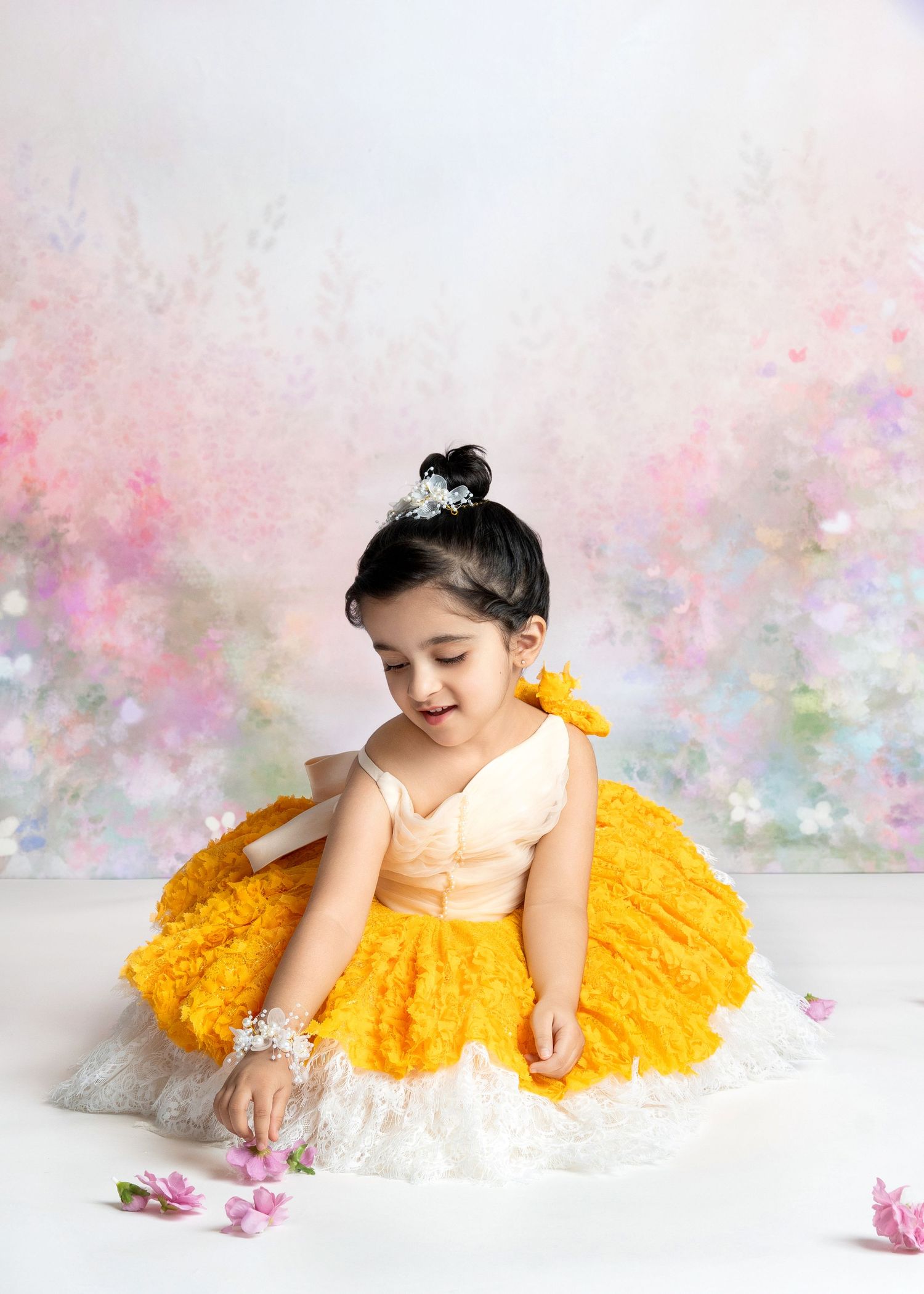 a young girl in a princess dress touches flower petals