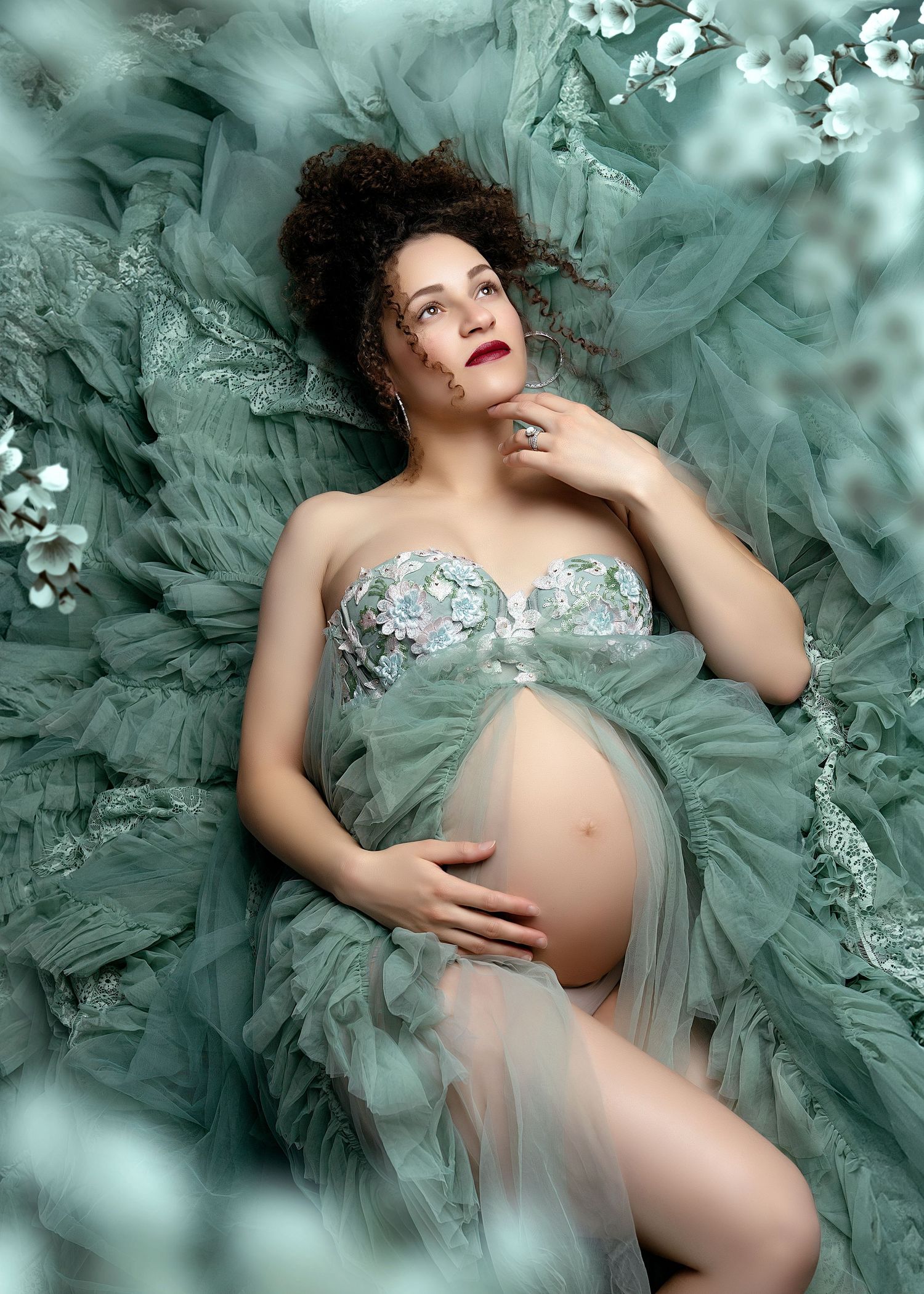 a pregnant woman lays in the layers of her gown's train