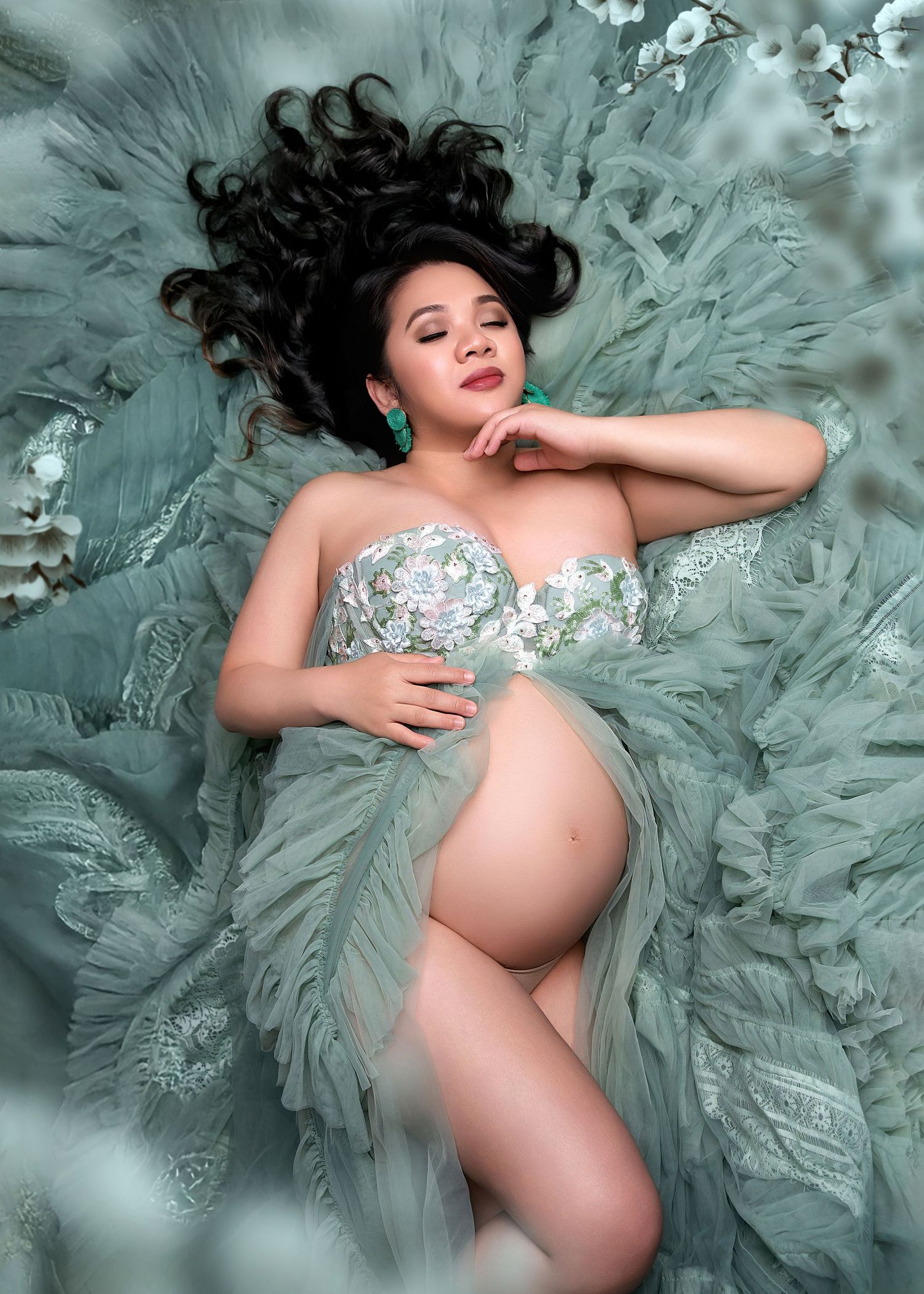 Maternity photo with dreamy teal tulle gown and crystal embellished bodice against soft ethereal background.