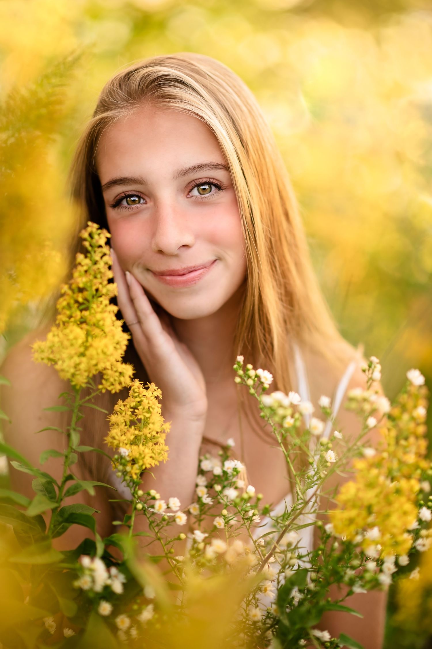 a young woman smiles with a hand resting on her face