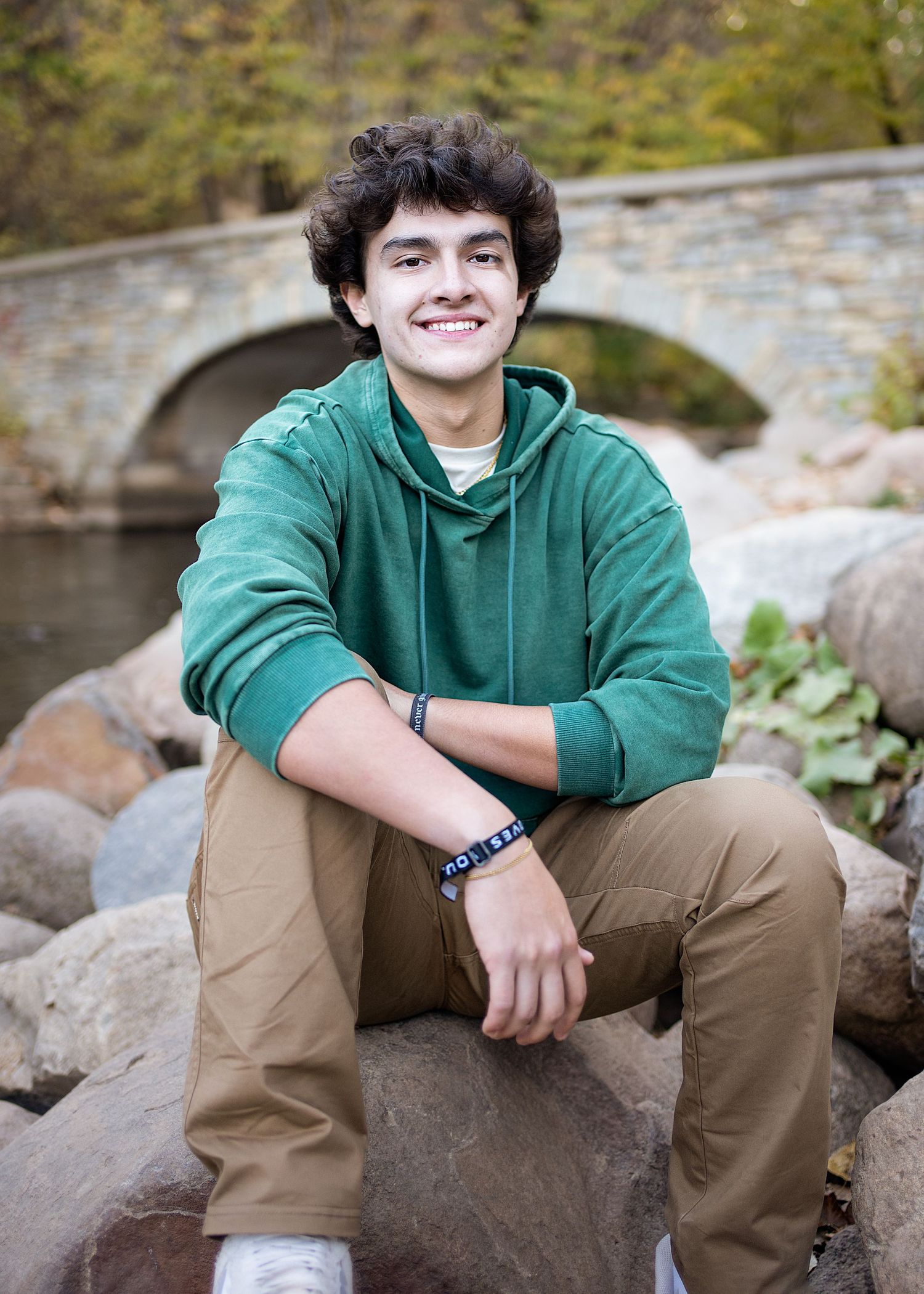 a senior boy sits on rocks during a session with a minneapolis photographer