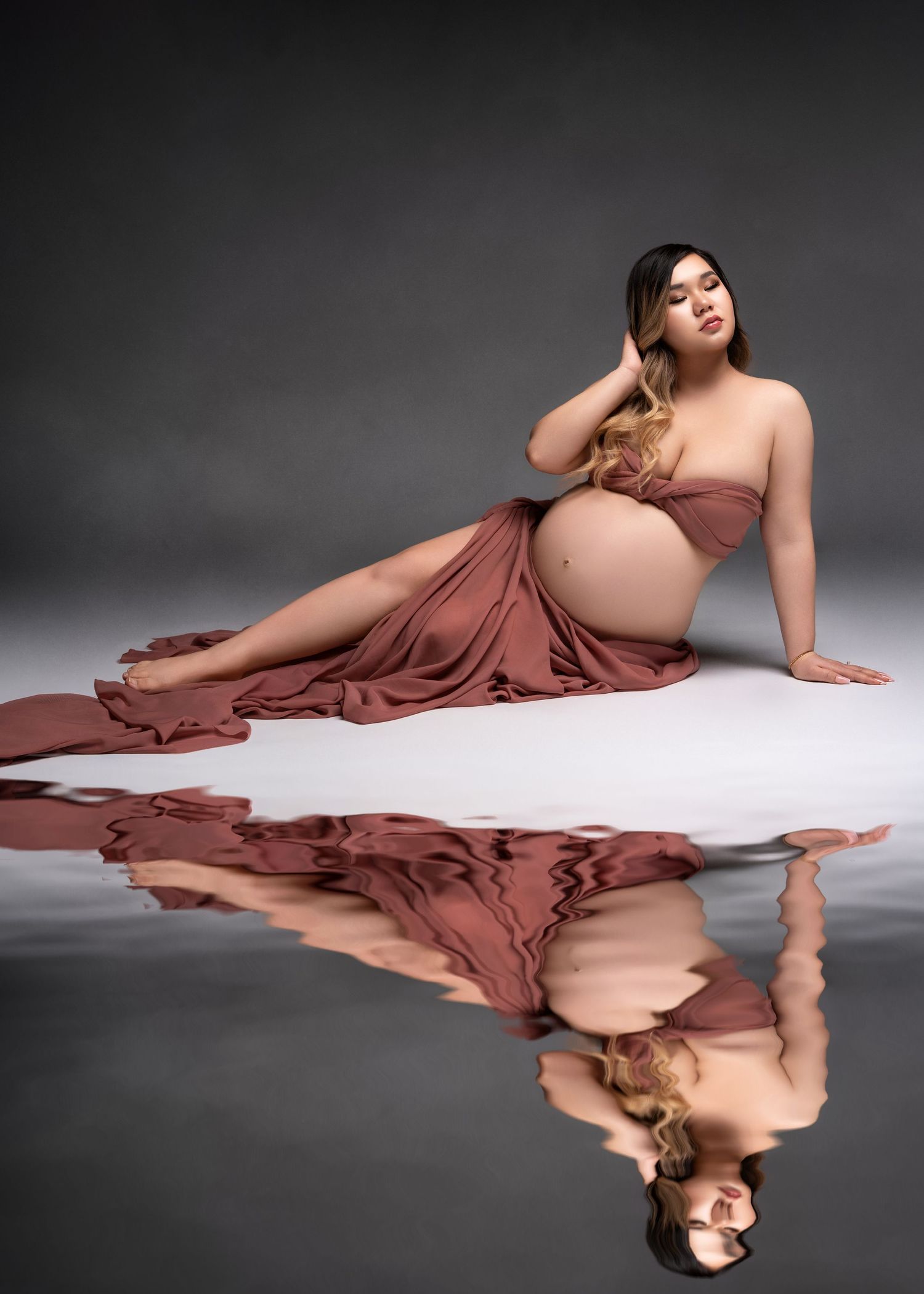 a woman lays in studio with her reflection rippling underneath her