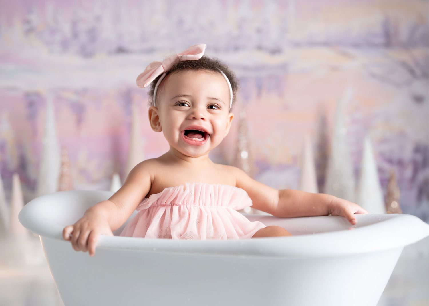 a young child smiles widely from a tiny bathtub